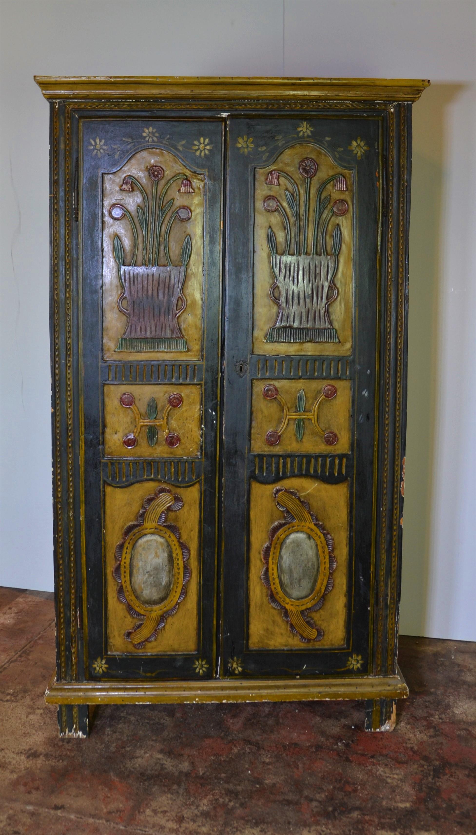 A Continental European armoire / cabinet with raised and painted decorations throughout. Various embossed motifs including urns and flowers done in an artistic style, 18th century.