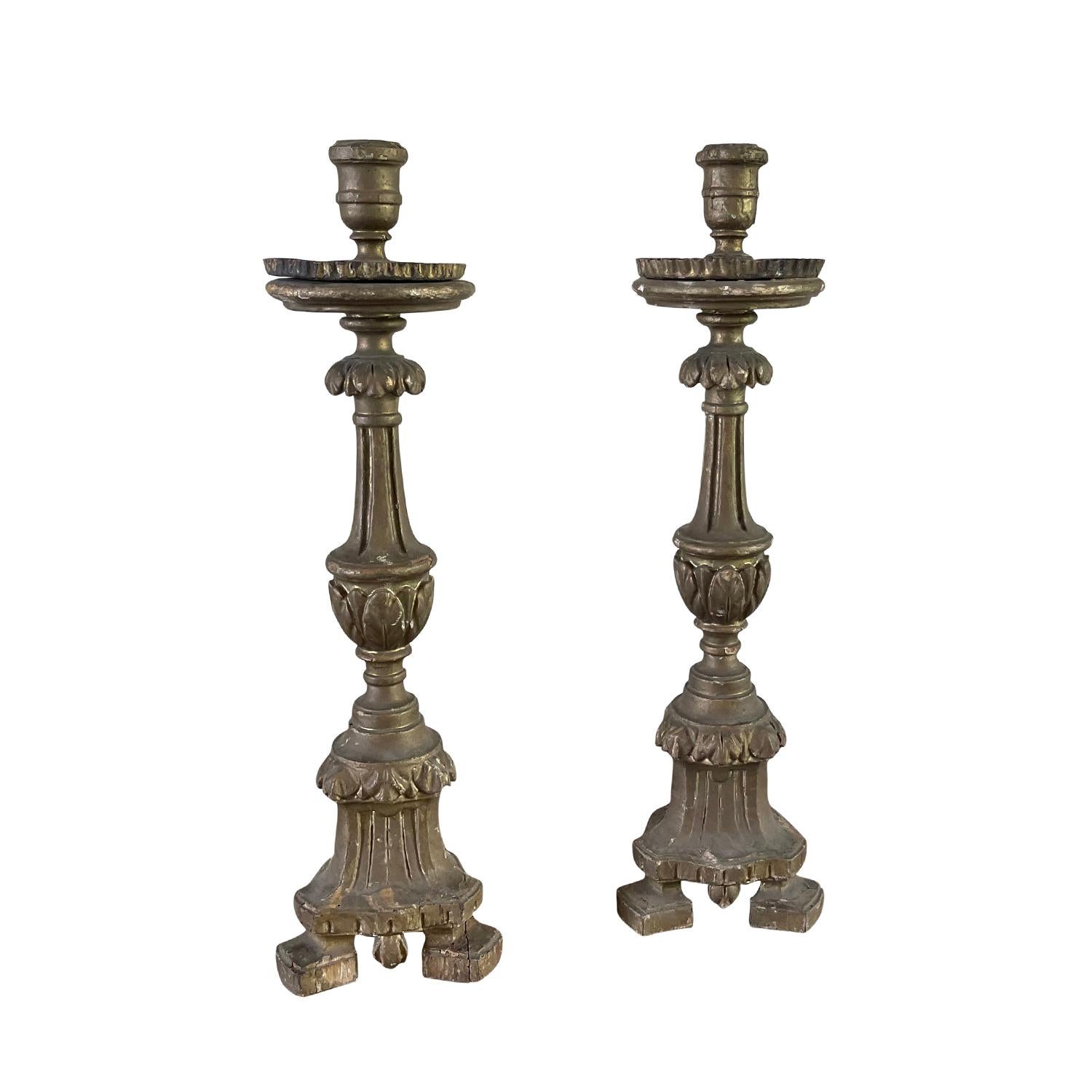 An antique French pair of mid 18th century candlesticks made of hand crafted Pinewood, in good condition. These candle holders feature a painted structure delicately on a tripod base. These décor pieces will bring an elegance to any table. Wear