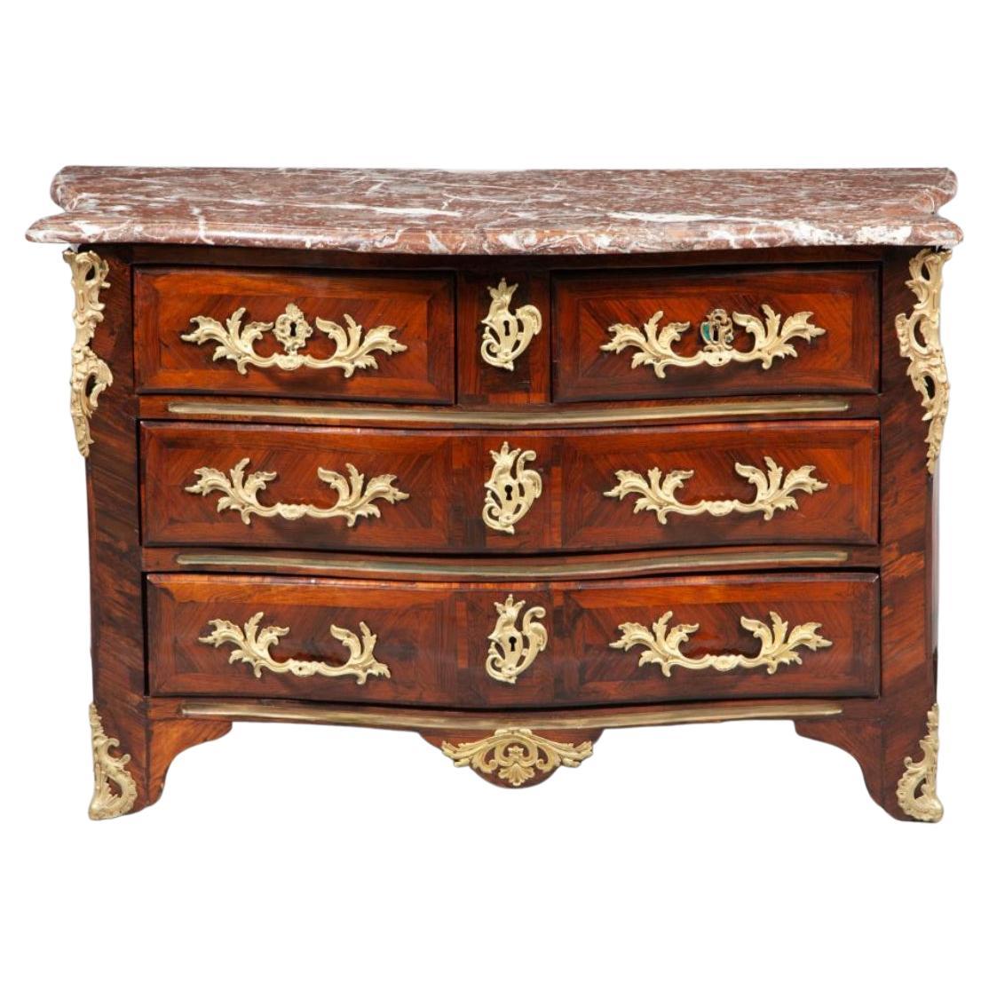 Nous vous présentons un meuble étonnant et rare qui incarne l'élégance et la sophistication du design français du XVIIIe siècle - la Commode française du début du XVIIIe siècle avec incrustation de bois de rose.

Fabriquée en chêne et dotée d'une