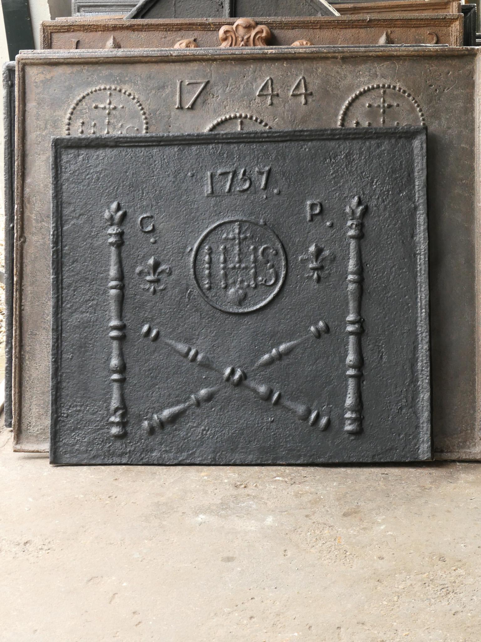 Plaque de cheminée Louis XV du XVIIIe siècle avec deux piliers, un monogramme IHS, une croix et la date de production 1757.

Le monogramme IHS signifie Iesus Hominum Salvator (Jésus Sauveur de l'humanité) ou In Hoc Signo (Dans ce signe tu gagneras).