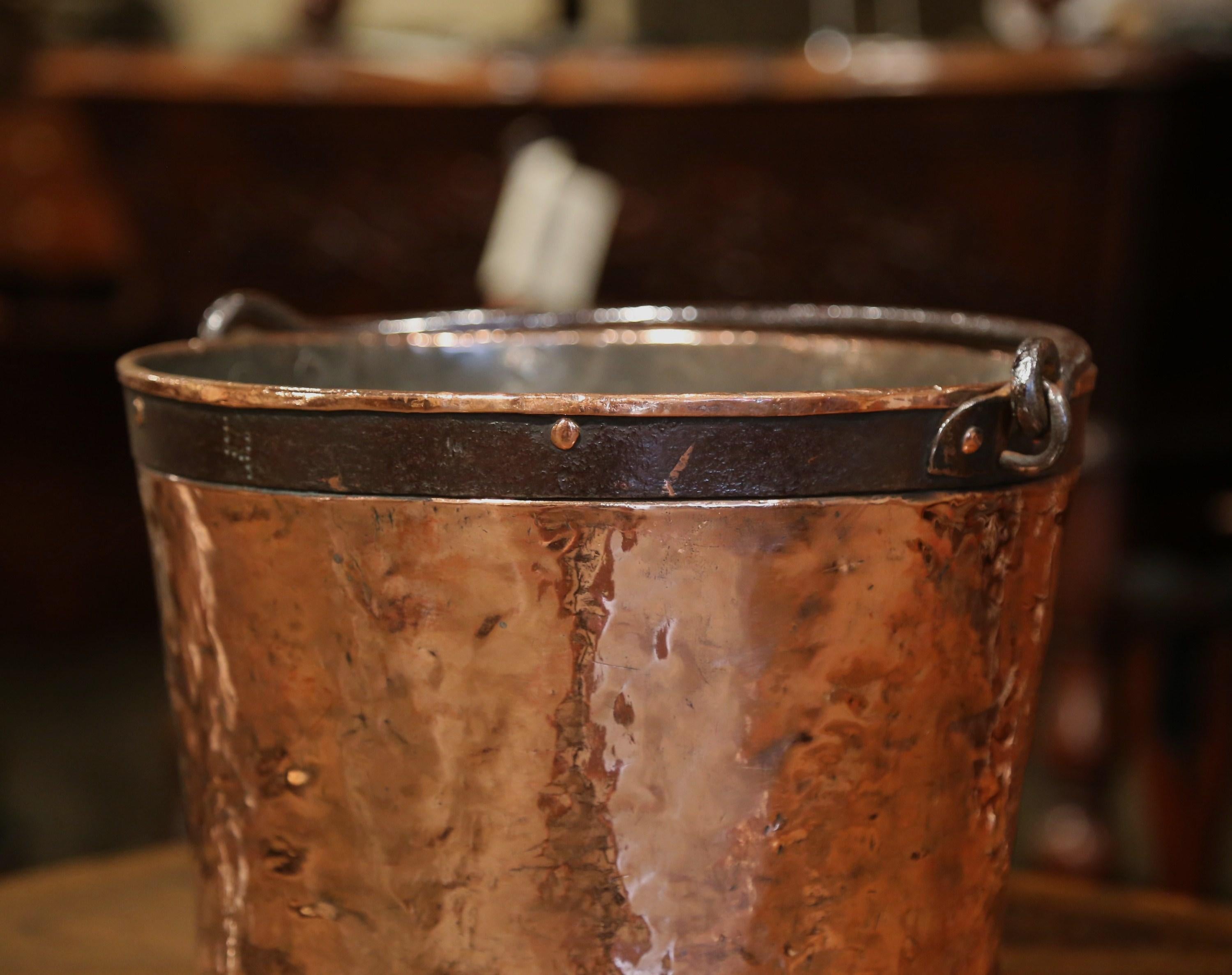 Use this versatile antique bucket as a cache pot or a waste basket. Crafted in Normandy France circa 1780, and made of copper and iron, the piece features a forged handle and two decorative iron rings at the top and bottom. The elegant measure