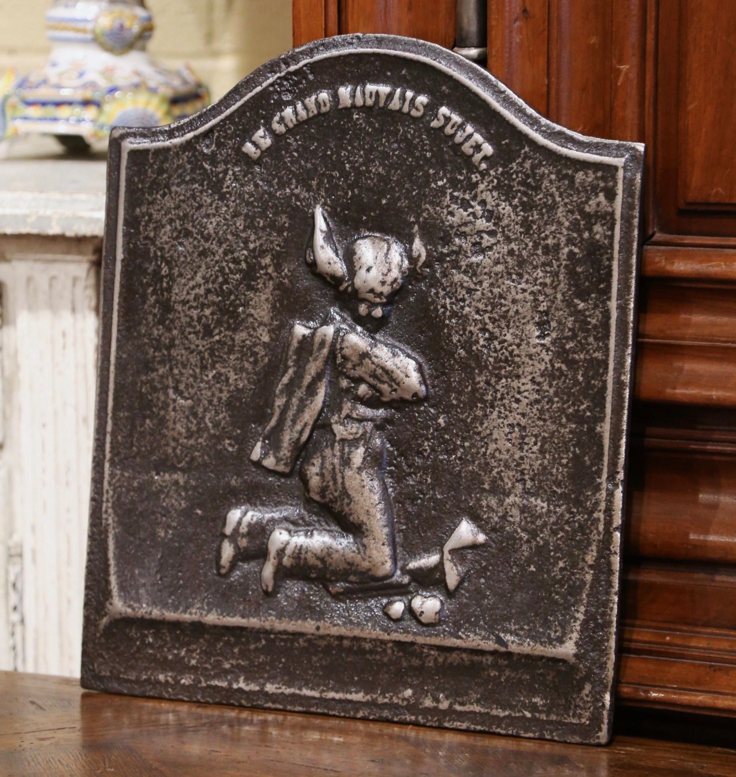 Decorate a fireplace hearth with this antique fire back, created in France circa 1760, and rectangular in shape with an arched top, the iron plaque is decorated with a carved representation of Beelzebub with the top inscription reading 