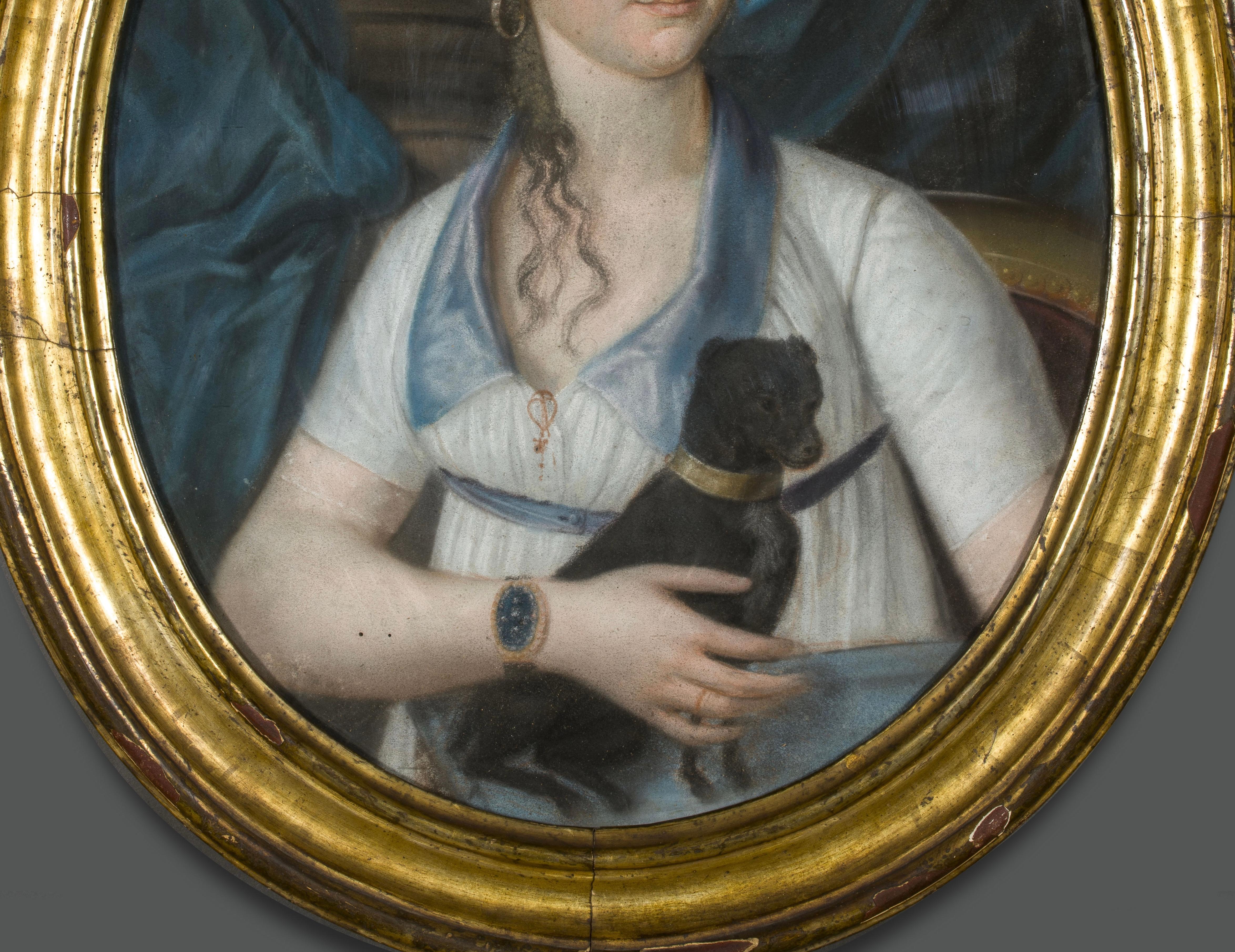 Beautiful pastel in an oval shape.
It depicts a young noblewoman portrayed three-quarter-length with her little dog in her arms.
Seated in a gilded armchair, she is draped in a background that reveals a classical column, while she flaunts her