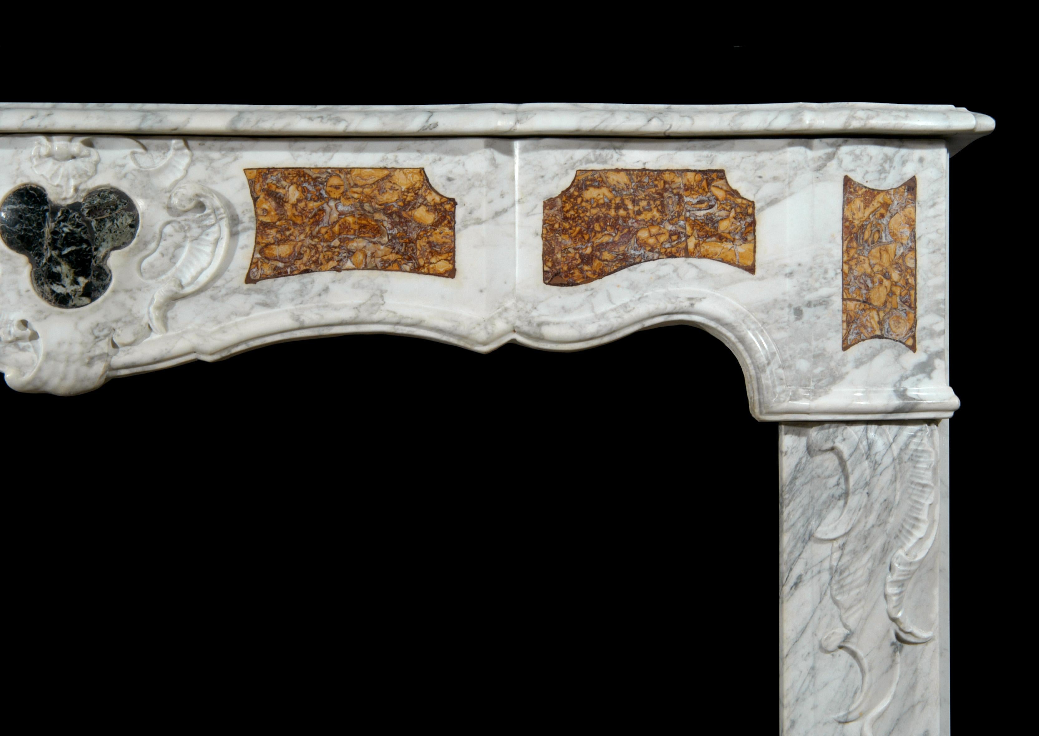 Ein französischer Kamin aus provenzalischem Carrara-Marmor aus dem 18. Jahrhundert, mit Einlegearbeiten aus Brocatelle und dunkelgrünem Marmor an Fries und Pfosten. Geschnitztes Motiv in der Mitte des Frieses und geschnitztes Scroll-Motiv auf der