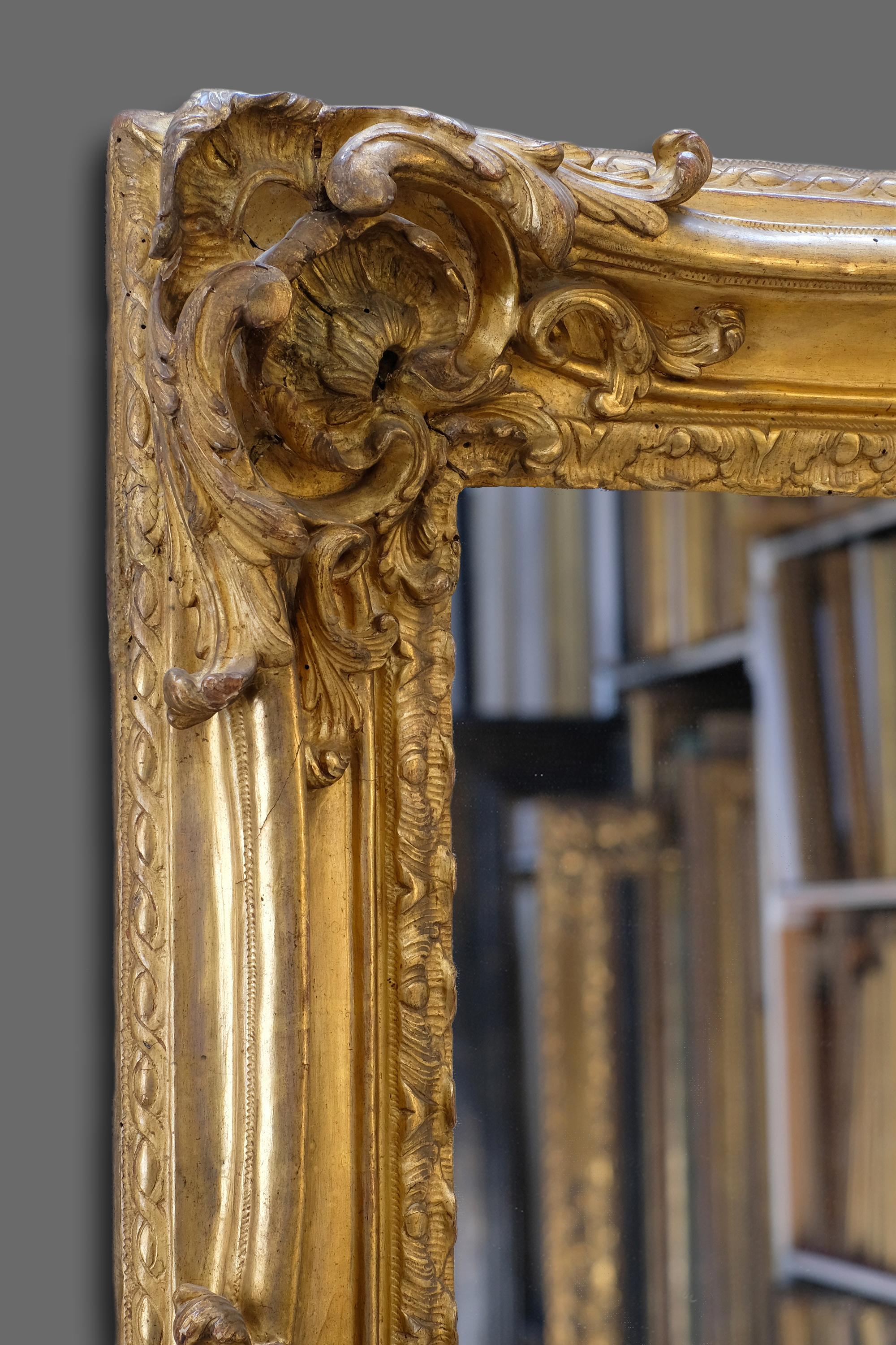 A very elegant and finely hand carved 18th century French Provençal Louis XV Rococo frame. It has a concave profile with carved corner and centre openwork cartouches with foliate scrolls, shells and rocailles on a channeled ground, linked by swept