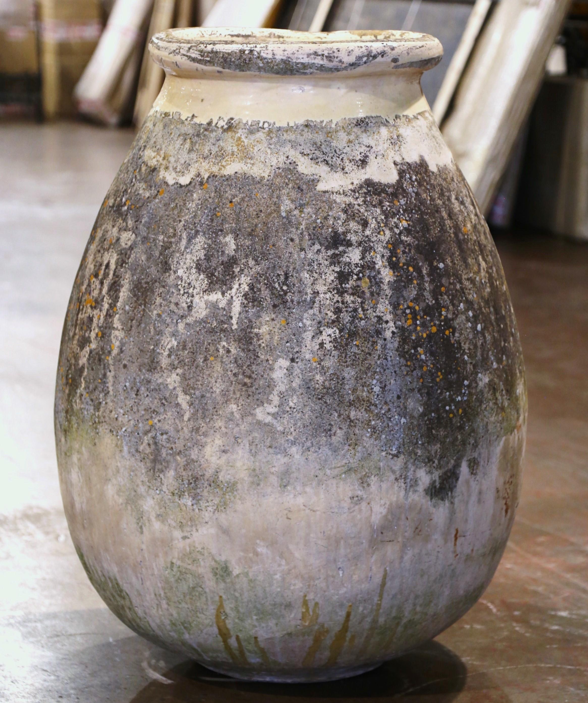 Cette grande jarre à olives ancienne en faïence a été créée à Biot, en Provence, dans le sud de la France, vers 1760. Fabriqué en argile blonde et de couleur neutre, le récipient en terre cuite a une forme ronde et bulbeuse traditionnelle. Ce pot