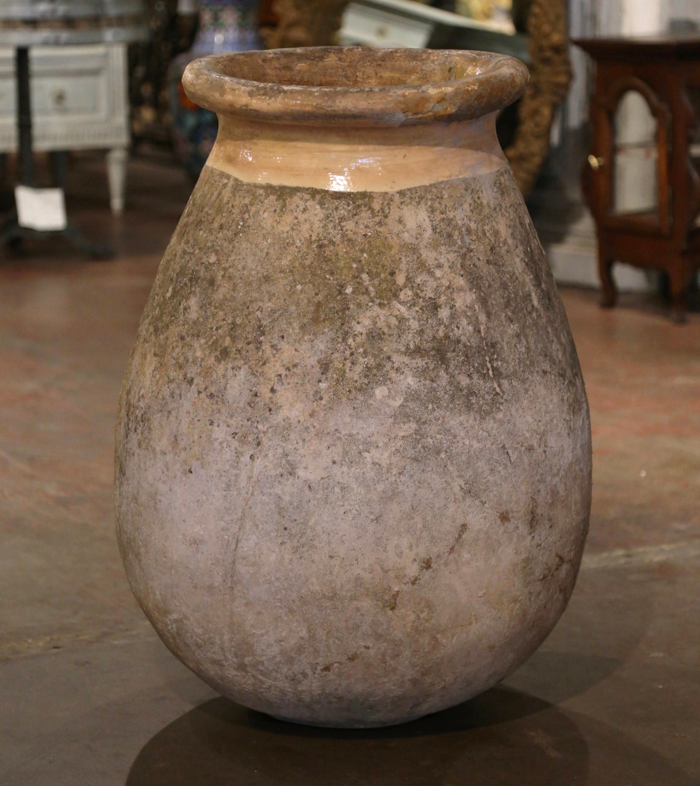 Dieser große, antike Olivenölkrug aus Steingut wurde um 1760 in Biot, Provence, Südfrankreich, hergestellt. Die farbneutrale Terrakotta-Vase aus blondem Ton hat eine traditionelle runde, bauchige Form. Die rustikale, von der Zeit gezeichnete Kanne