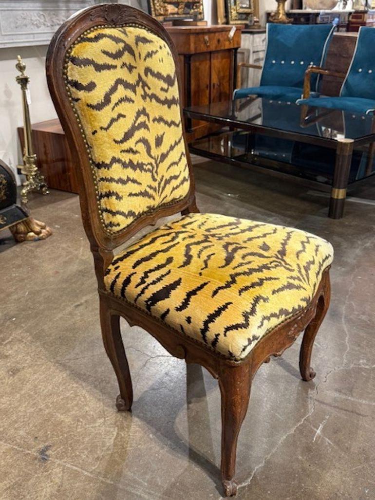 This 18th century French Provincial carved walnut side chair is a beautifully crafted piece of furniture designed for adults. The intricate carvings and rich walnut finish give it a timeless and elegant look, perfect for any home. Upholstered in a