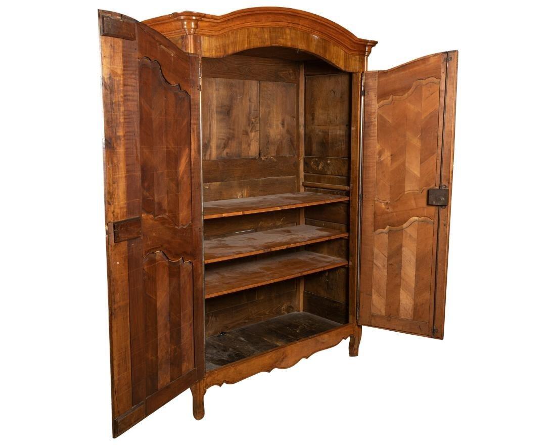 Excellent condition 18th century French Provincial armoire in cherrywood. Paneled sides and doors in a herringbone style pattern. Cast iron door length hinges and eschutchens. One key to the working lock. Three adjustable shelves. Arched capitol on