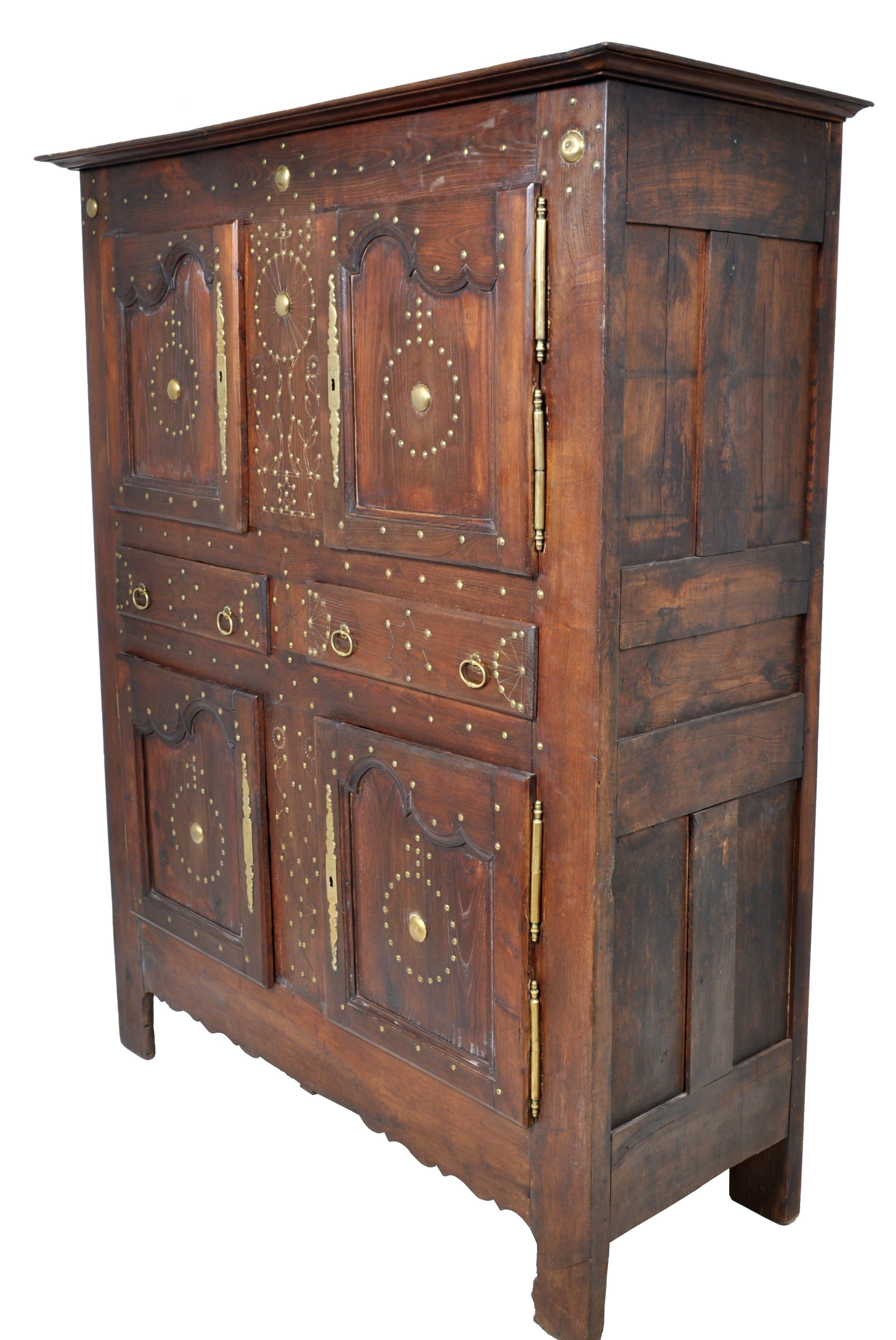 A most unusual 18th century French, Brittany, Provincial chestnut cabinet, circa 1720. The cabinet with original brass stud-work decoration. Twin cupboards over twin cupboards, each having a shaped paneled door with long engraved brass escutcheons,