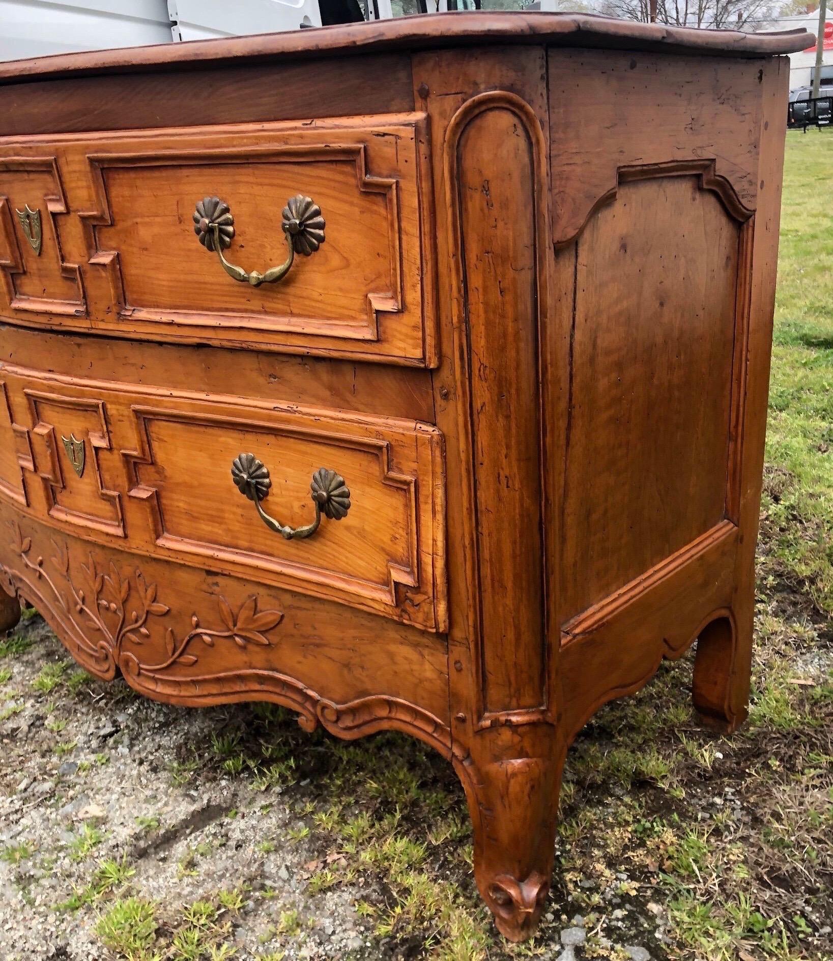 Magnifique commode à deux tiroirs en bois fruitier de style provincial français du XVIIIe siècle, avec dessus façonné, pieds à volutes et tablier sculpté de branches, de volutes en 