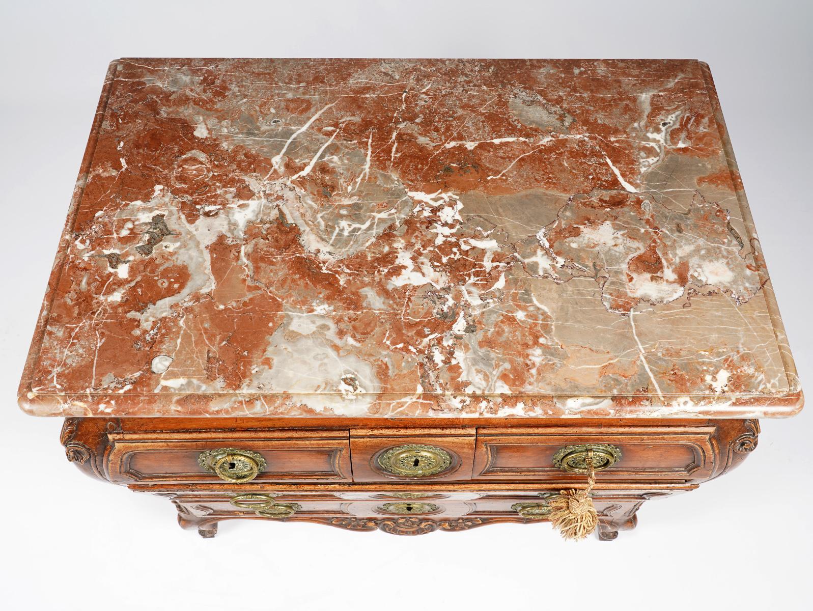 This French Provincial fruitwood marble-top commode is fashioned in the baroque style with elements from the Louis XV period. It dates to the first half of the 18th century. The commode features a gorgeous molded edge marble top above a richly