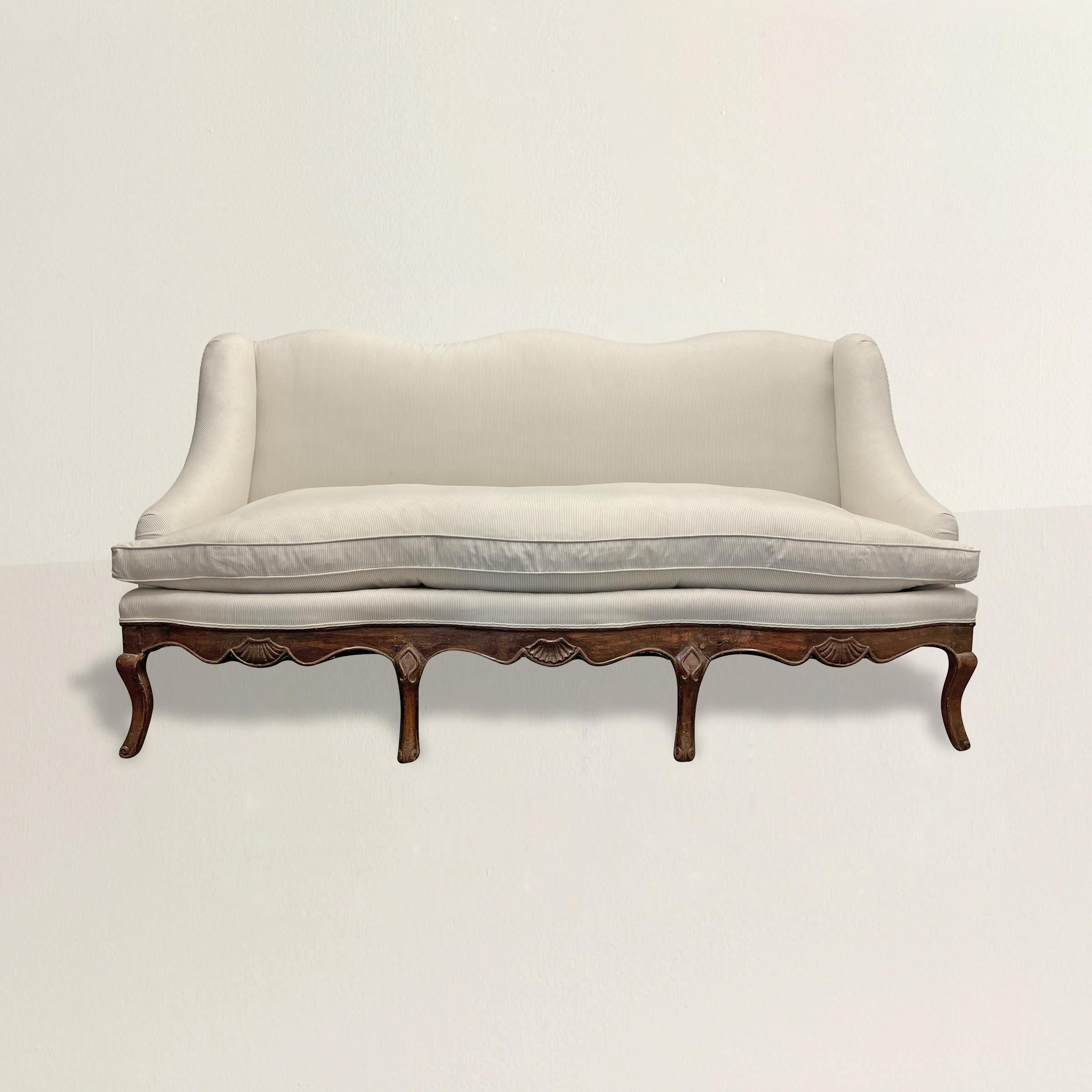Transport yourself to the opulence and sophistication of 18th century France with this exquisite Louis XV sofa, a testament to the era's grace and elegance. Its curvaceous serpentine shape and perfectly pitched back epitomize the Rococo style, while