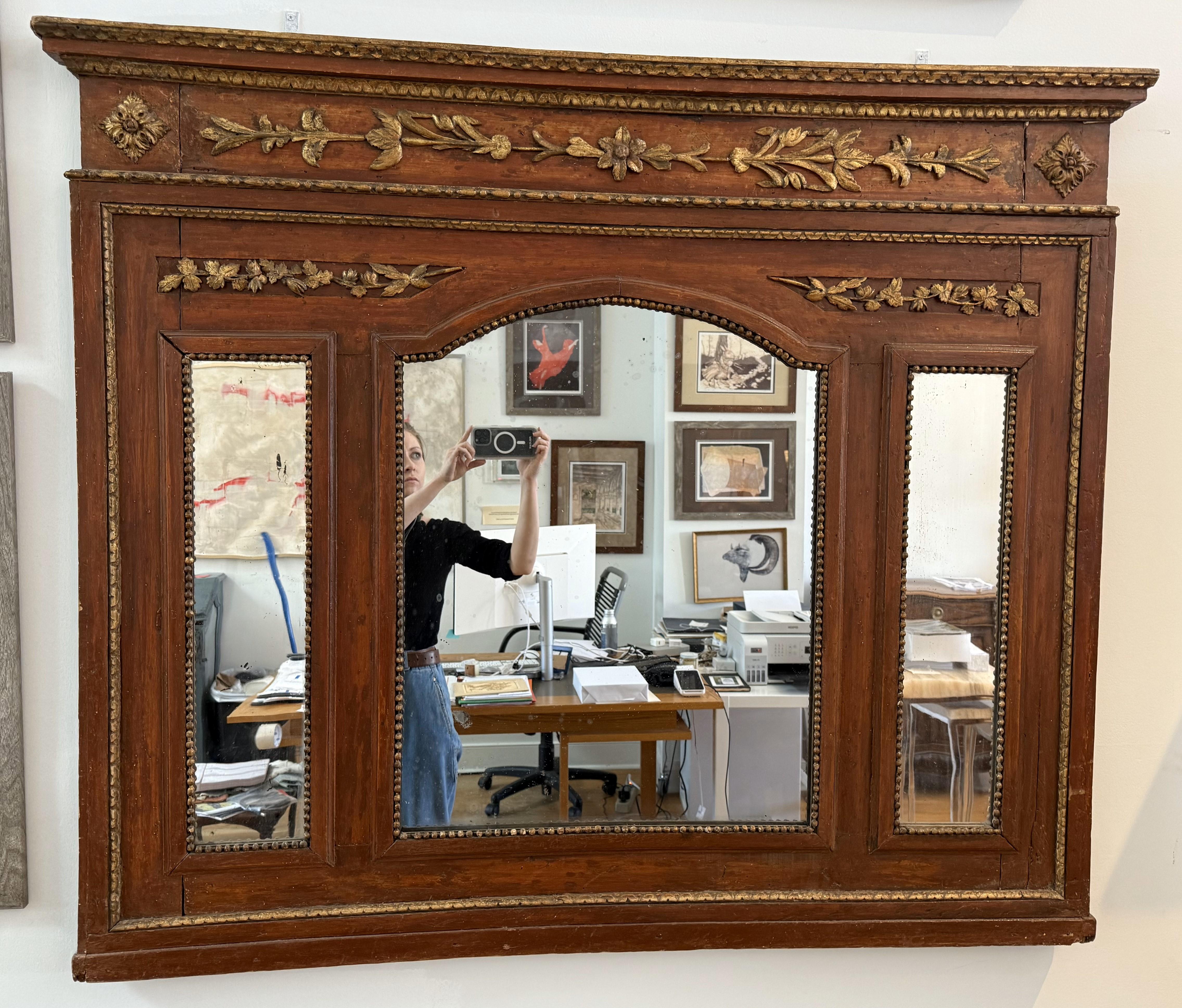 Specchio Trumeau del XVIII secolo, periodo Luigi XVI. Decorazioni finemente intagliate e modellate che conservano la doratura originale e la calda finitura verniciata di rosso. Forma insolita con l'originale piastra centrale ad arco e una più