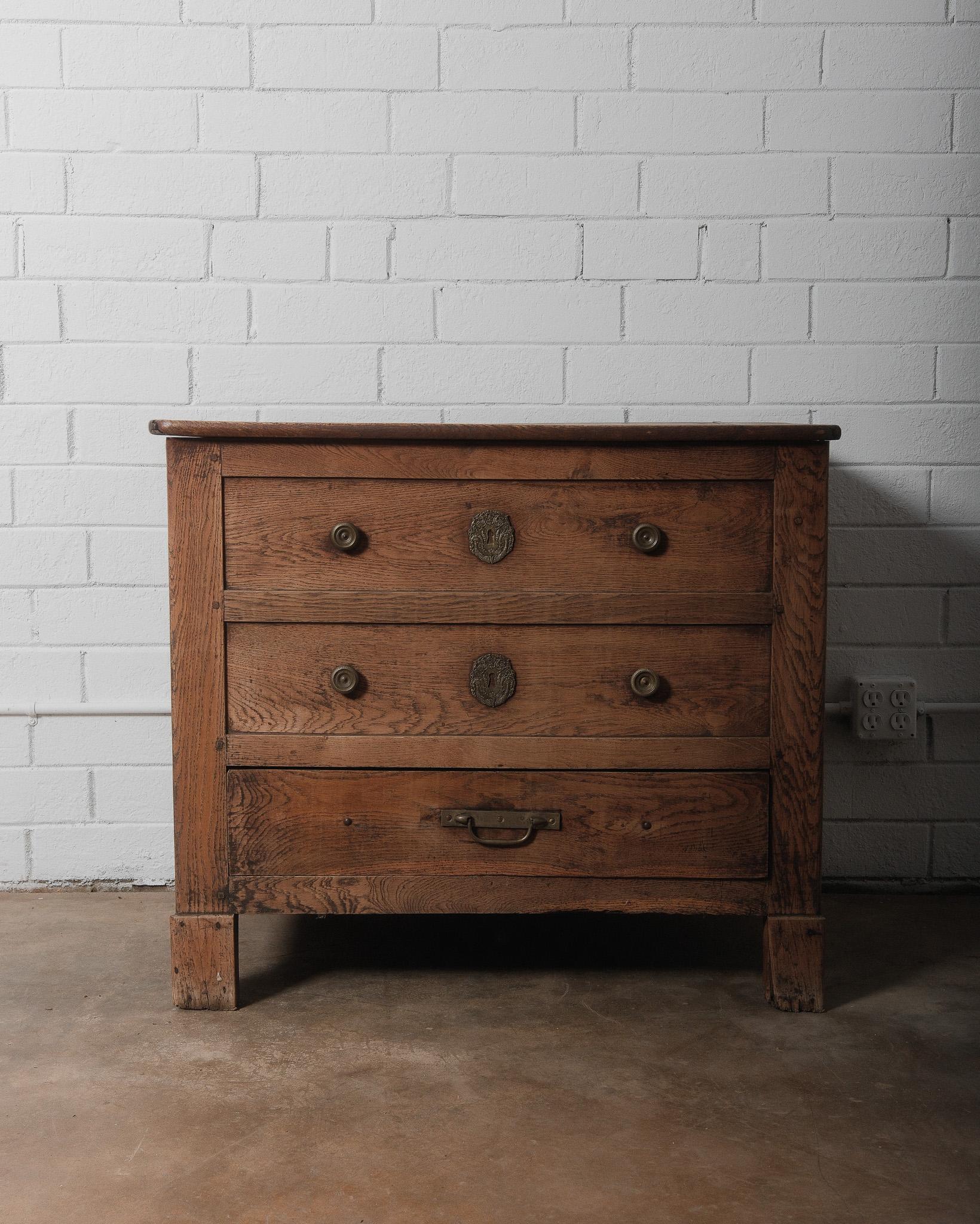 This beautifully aged French Provincial coffer chest is a stunning example of 18th-century craftsmanship, likely originating from rural France or Belgium. Made of solid oak, it features a lift-top storage compartment above three drawers, seamlessly