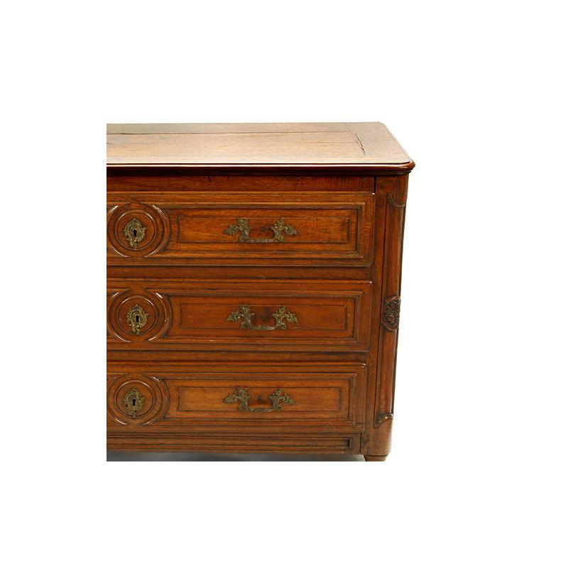 18th century French Provincial oak commode. 
Rectangular moulded top over three carved long drawers mounted with bronze handles of a rocaille motif, on tapered turned feet.