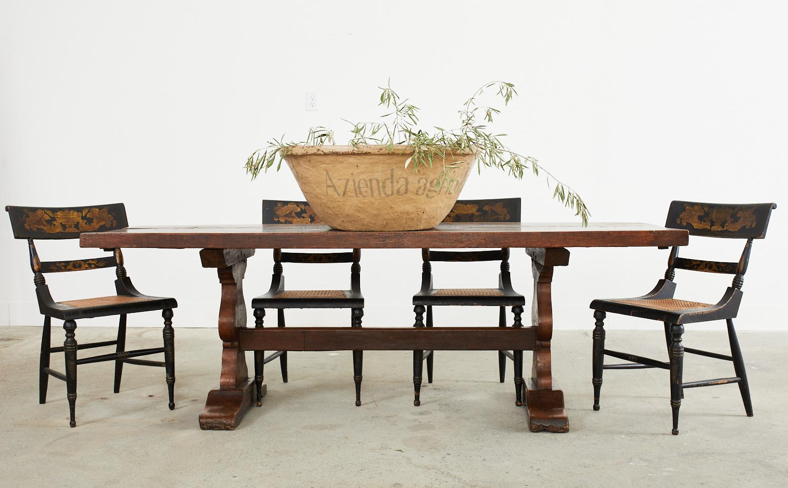 Rustic 18th century country French provincial farmhouse trestle dining table or refectory table crafted from hand-hewn oak featuring a 2.25 inch thick top. The trestle style base is constructed with an exposed mortise and tenon joinery. The thick
