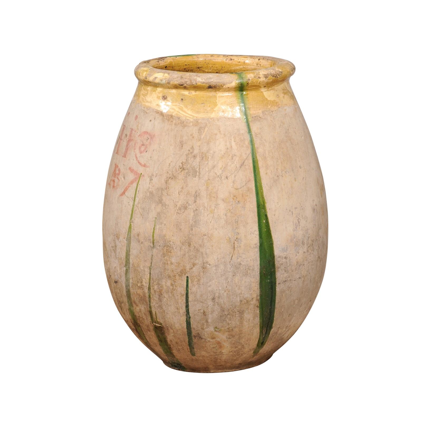 A large size French terracotta olive oil Biot jar from Provence with yellow glazed lip and green drippings from the 18th century. Emanating rustic Provencal charm, this large 18th-century French terracotta olive oil Biot jar captivates with its rich