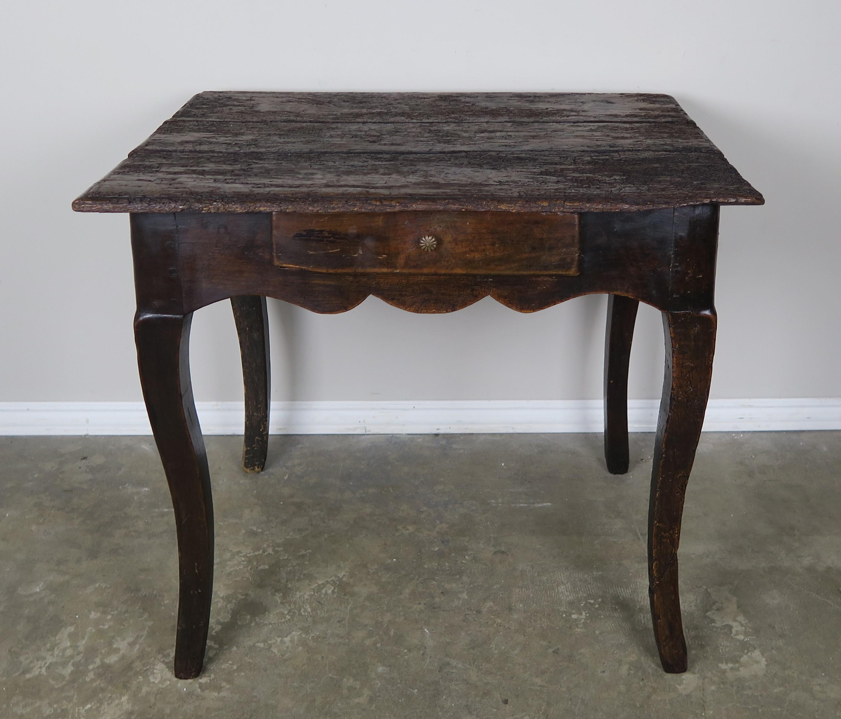 18th century French Provincial style table with drawer. The table stands on four cabriole legs with a scalloped apron. Worn, distressed finish.