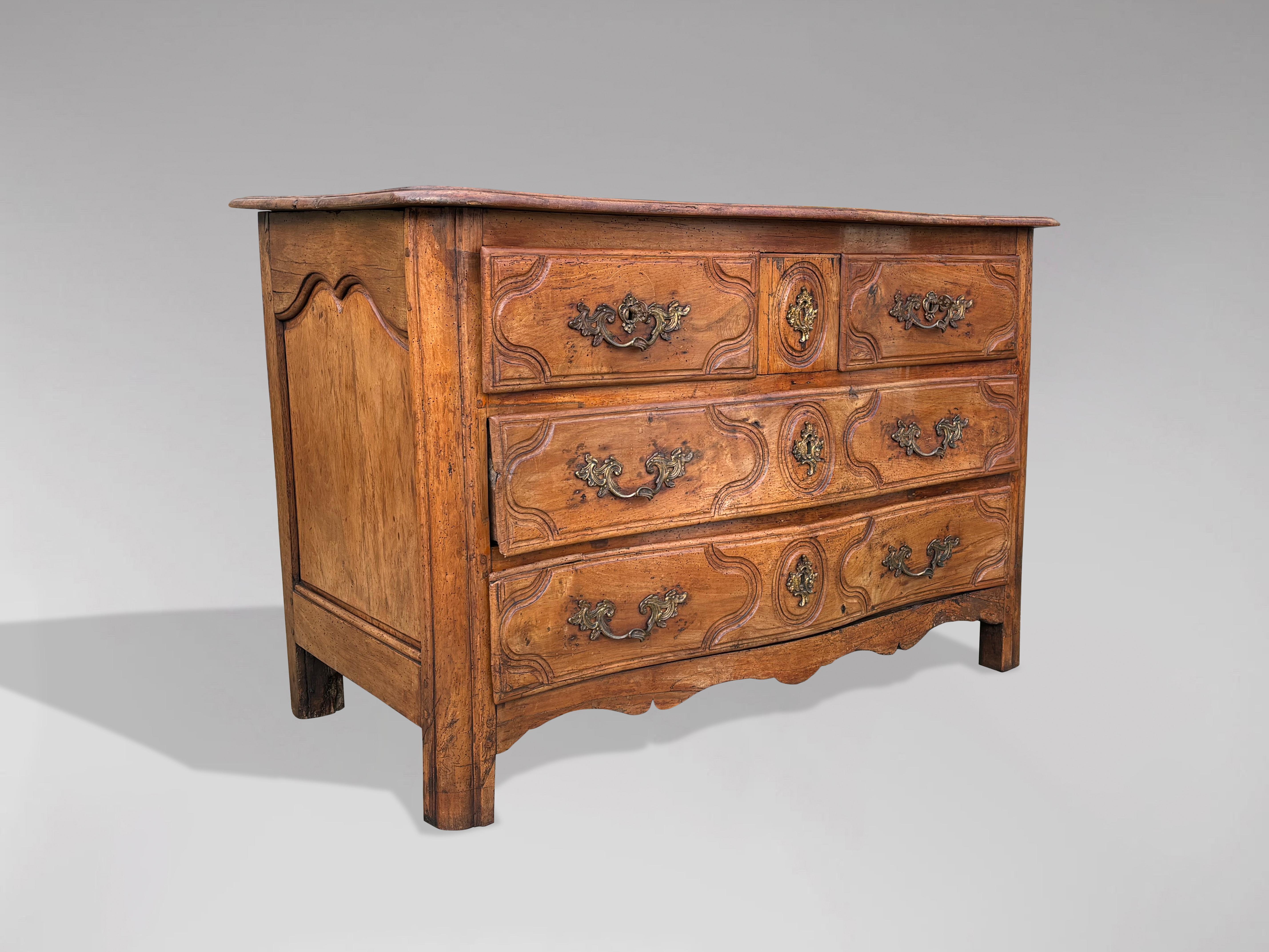 A mid 18th century walnut French provincial commode of the Louis XV period. This chest of drawers features three levels with a secret drawer situated between the top two drawers, reached by opening the drawers on either side first. The rectangular