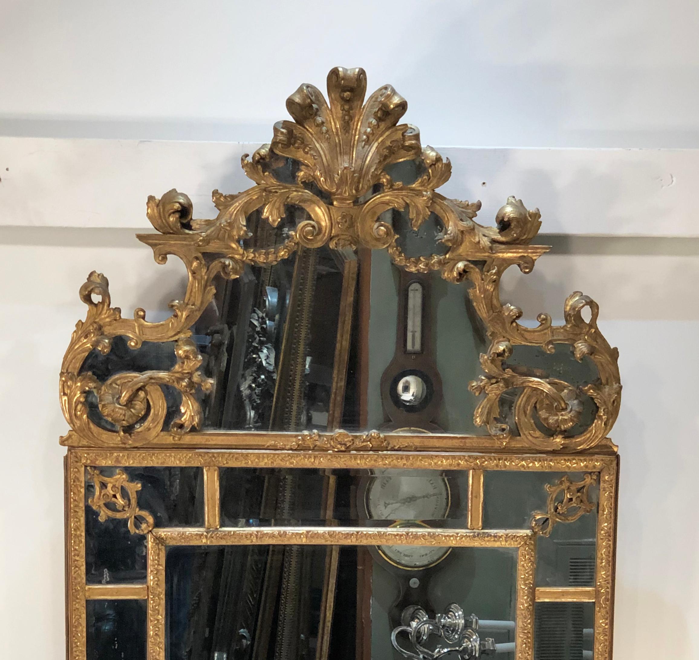 A Grande Scale French Régence looking glass is all carved giltwood with mirrored borders, circa 1715 - 1730. (see page pg. 185 of World Mirrors by Graham Child) The carved giltwood and mirror pediment can be removed from the top. The center looking