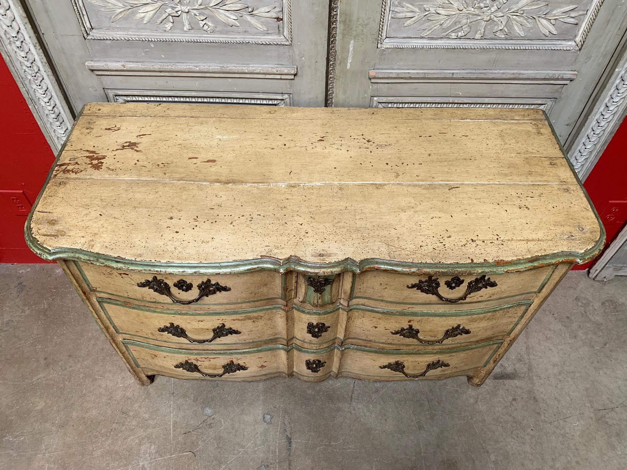 French period Regence three drawer commode with green and golden yellow old painted finish. This beautiful commode is a wonderful scale and has a great patina. The commode features a double serpentine facade with a carved cartouche between the top