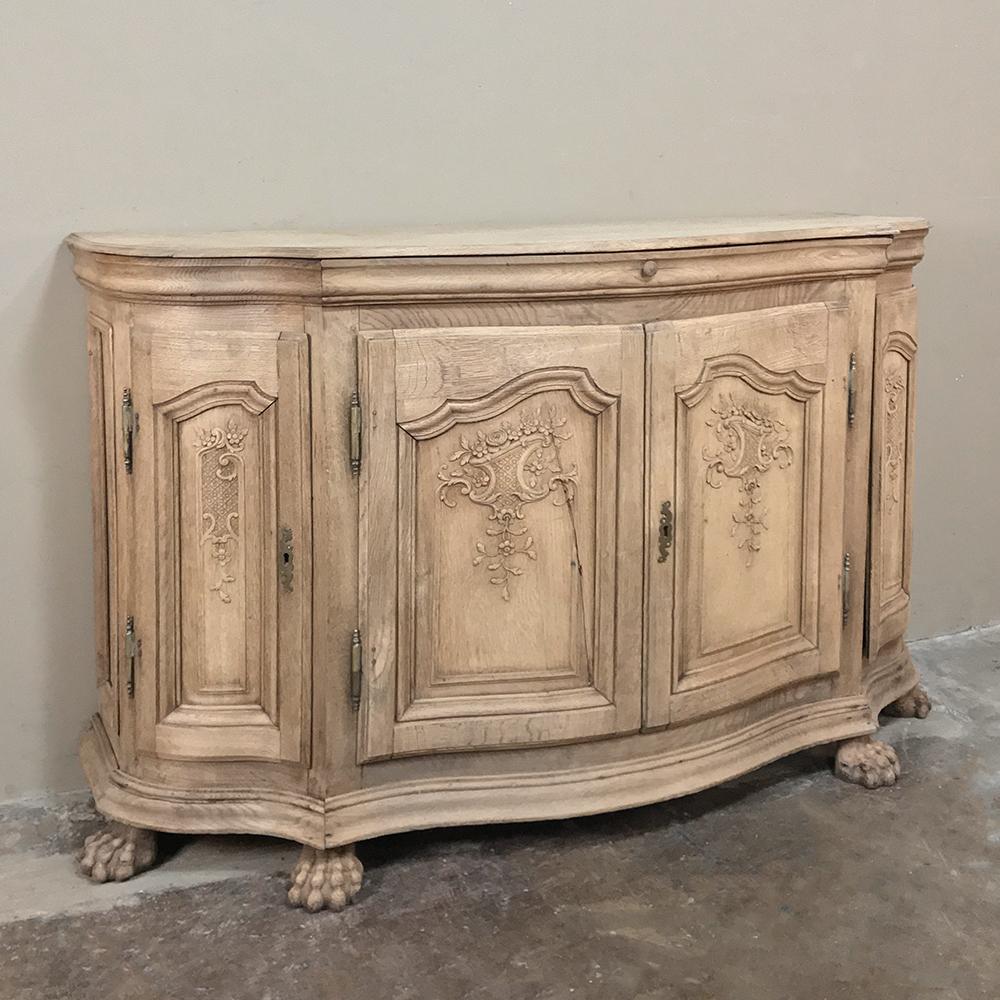 18th century French Regence demilune stripped oak buffet features an amazingly contoured facade, with serpentine sides and bowed front creating a variation on the demilune form. Bold molding frames the intricately hand-carved door panels exhibiting