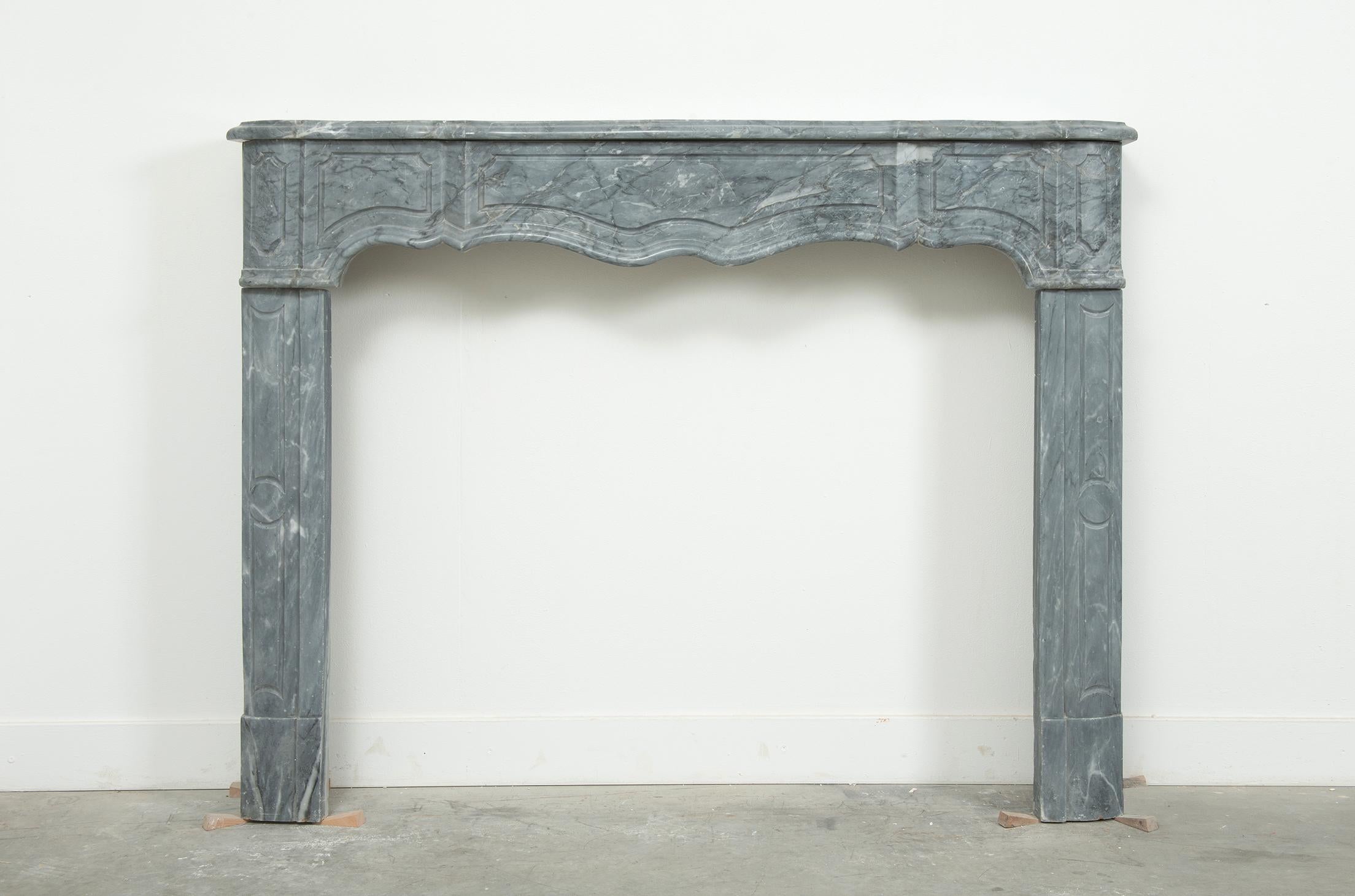 An exquisite 18th century French Régence style fireplace mantel crafted from luxurious grey Italian Bardiglio marble. This finely carved antique mantel embodies the elegance and refinement of the Régence period, making it a rare and highly desirable
