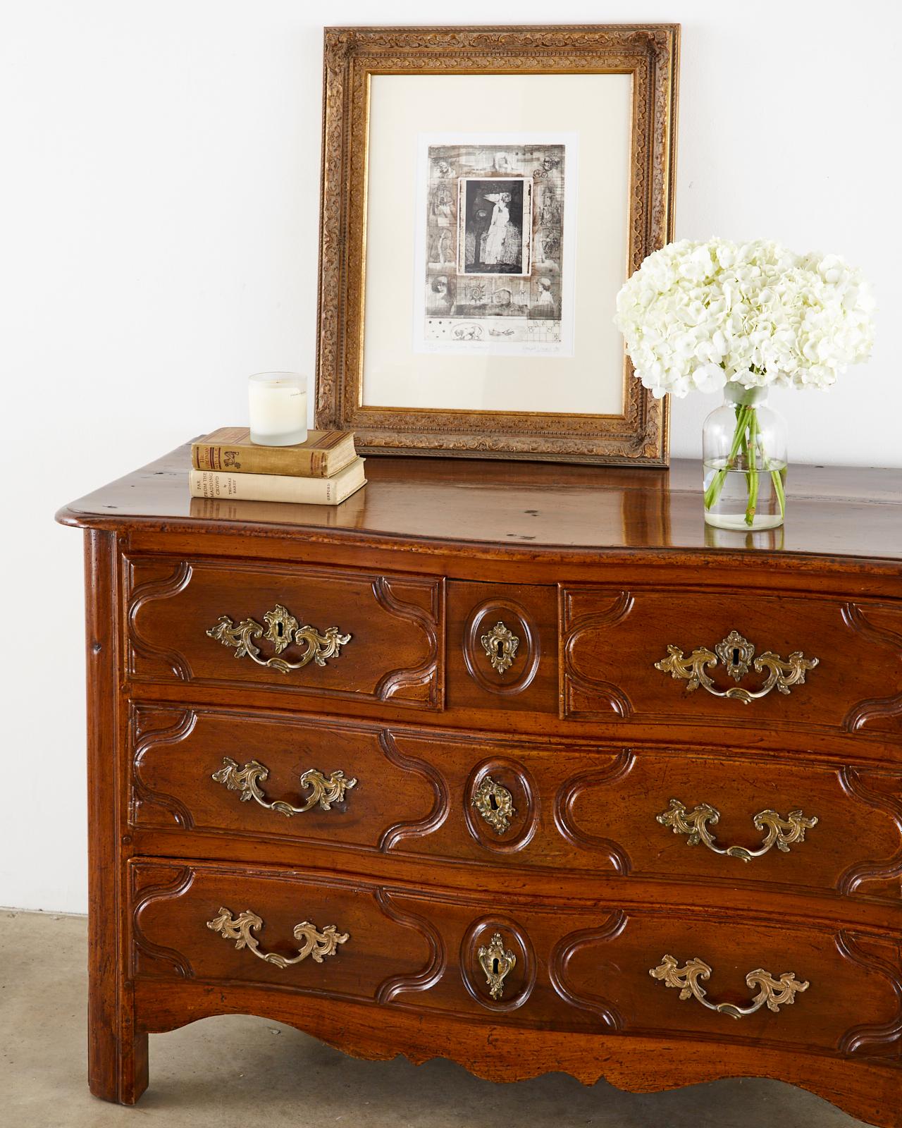 Handsome 18th century French Regence period commode or chest of drawers. Crafted from walnut in the transitional style between the heavy Louis XIV and the more Rococo influenced style of Louis XV. The case has a subtle serpentine form with peg