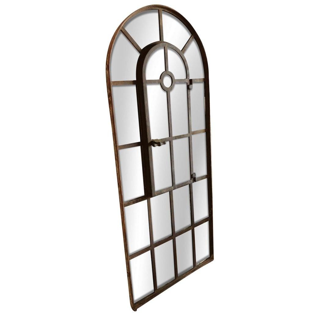 Late 18 Century, an antique French Orangerie wall mirror with an arched top, in good condition. The structure has a cast iron antique frame, with ecru colored aged painted patina, and newly inserted mirrored panels. The antique wall décor represents