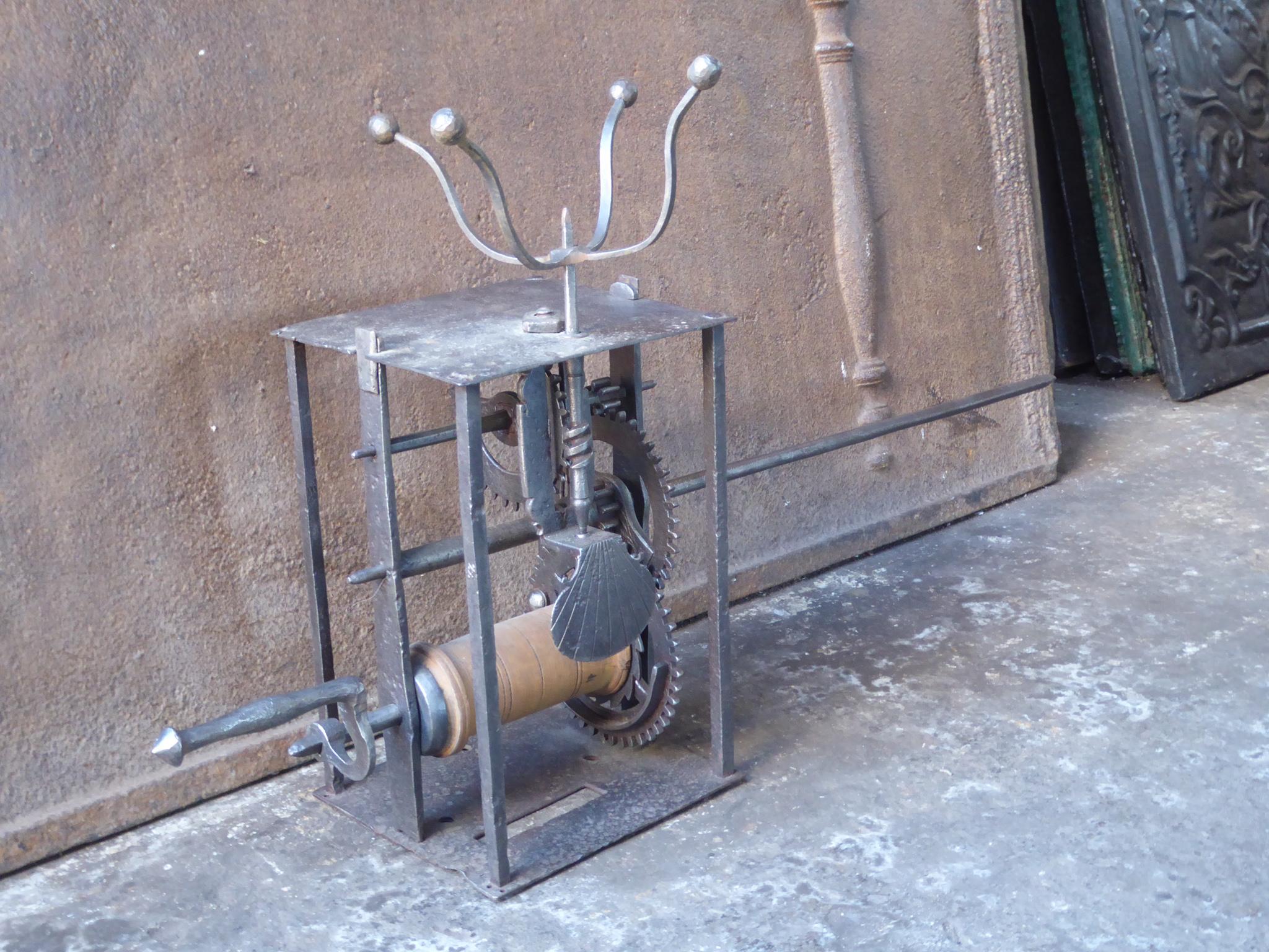 Beautiful 17th century French weight-driven spit jack made of wrought iron, wood and lead. With a scallop shell at the front. It was used for cooking in a kitchen fireplace. The mechanism is still functional, though it misses a rope and a wooden