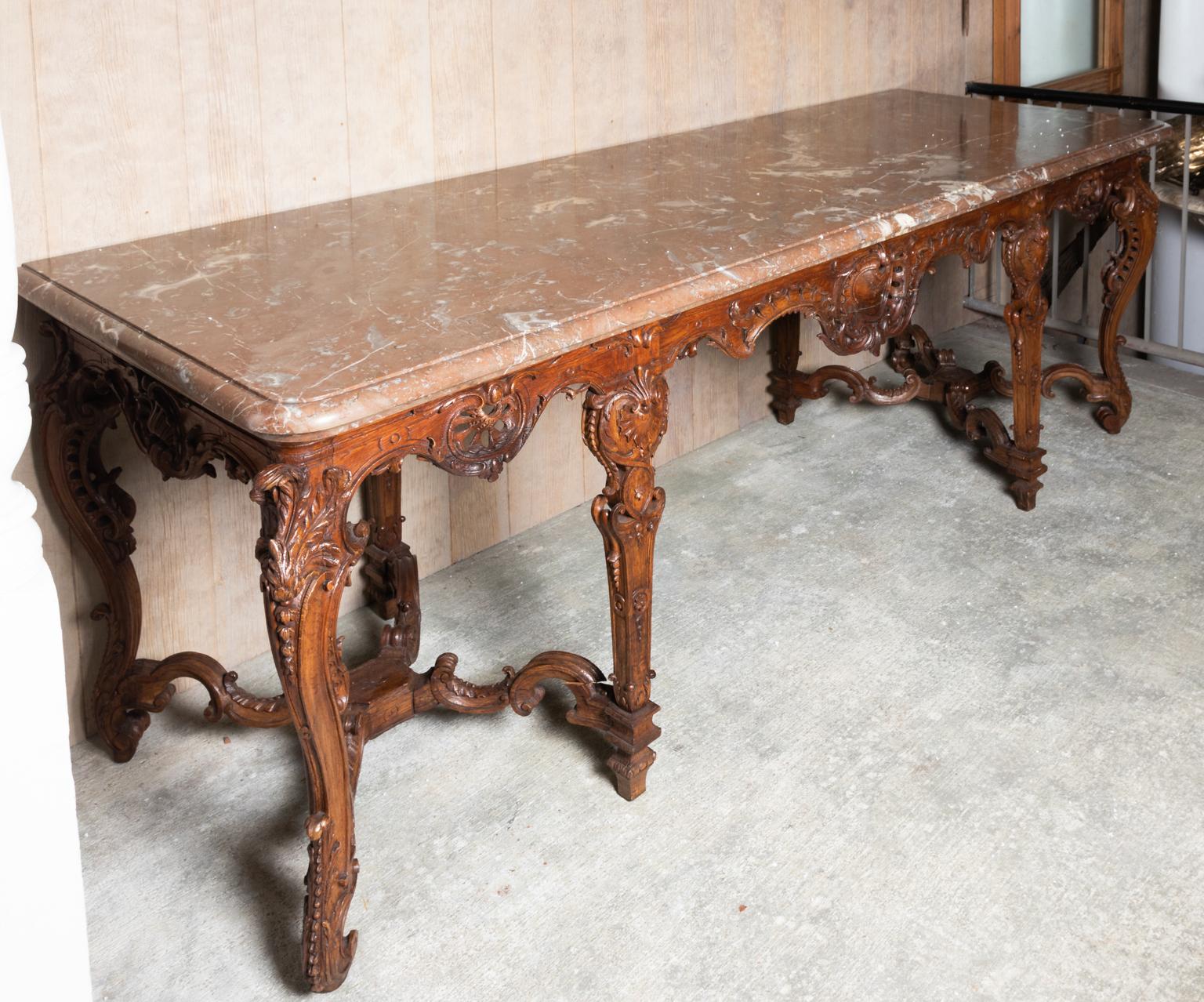 Large hall sized French Rococo style marble top console table for the hall with heavily carved scrolled foliage and shell work throughout. The piece of marble is also entirely one slab. Please note of wear consistent with age including scratches and