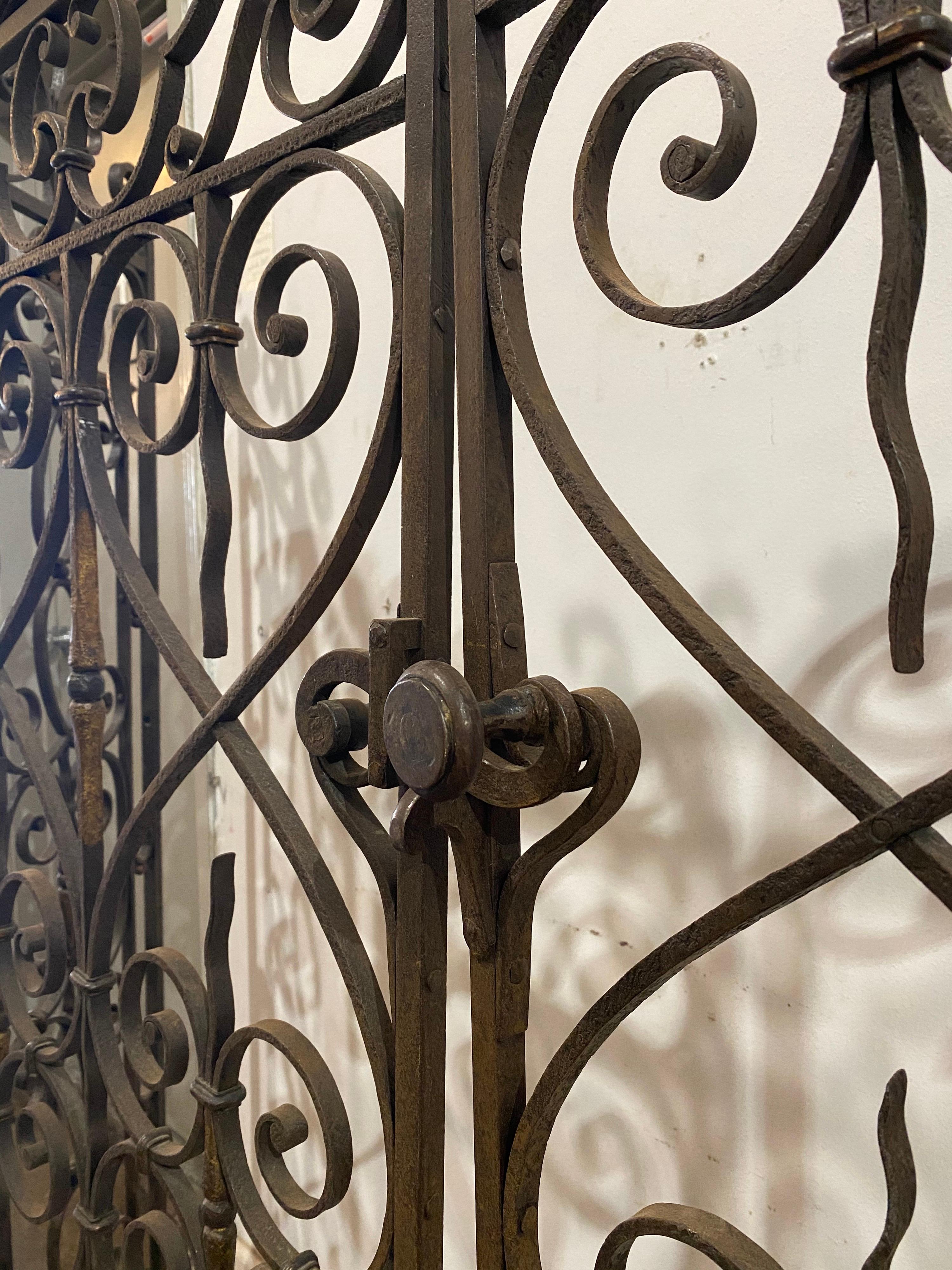 A pair of 18th century French style gates with iron scroll design and floral accents.