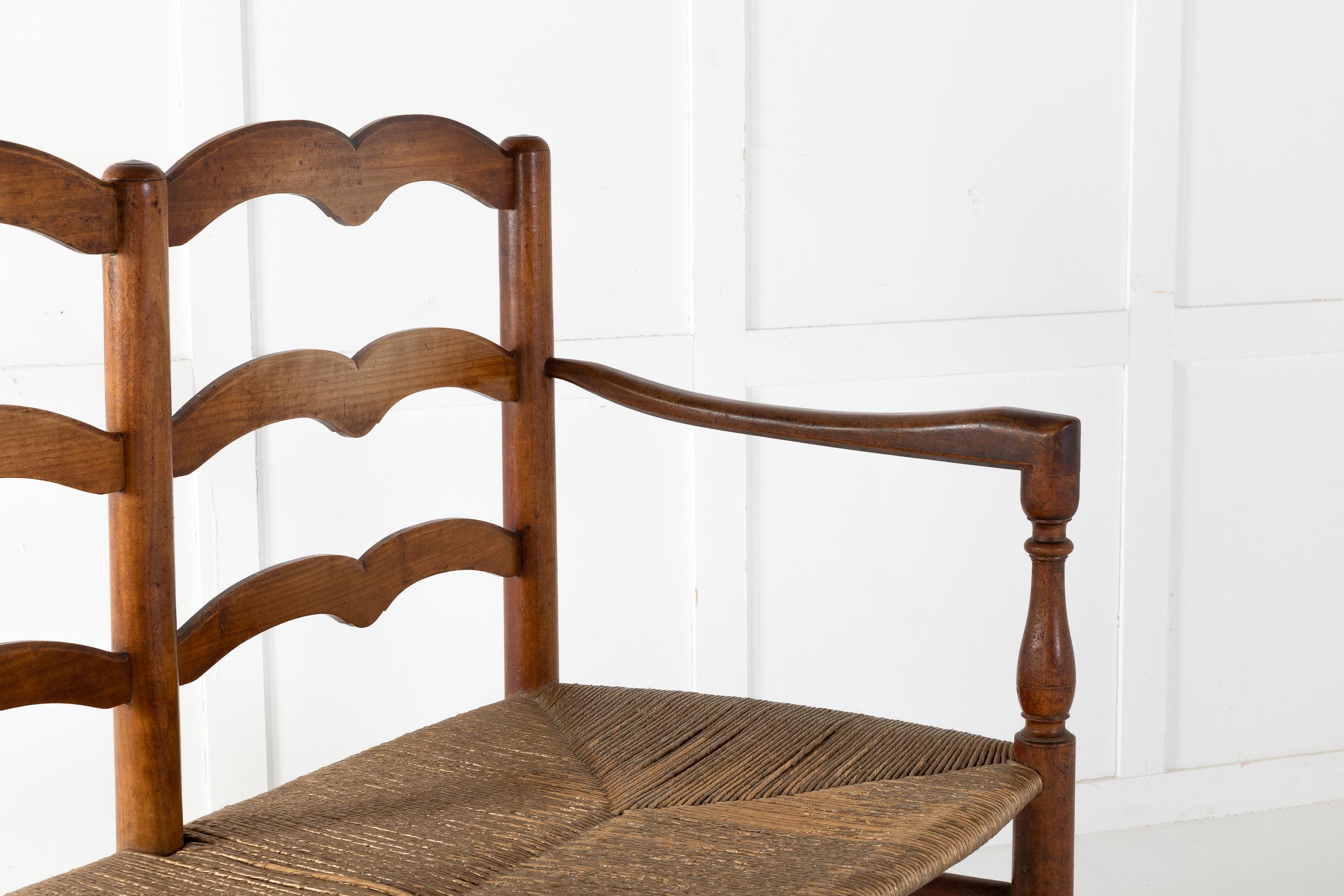 Beautiful, simply shaped French rush seat, ladder back, cherry bench. Seats three and features a handwoven rush seat and ladder-back. A wonderful rustic look that captures the feeling of rural, France. Simple yet sophisticated. Measures: Seat height