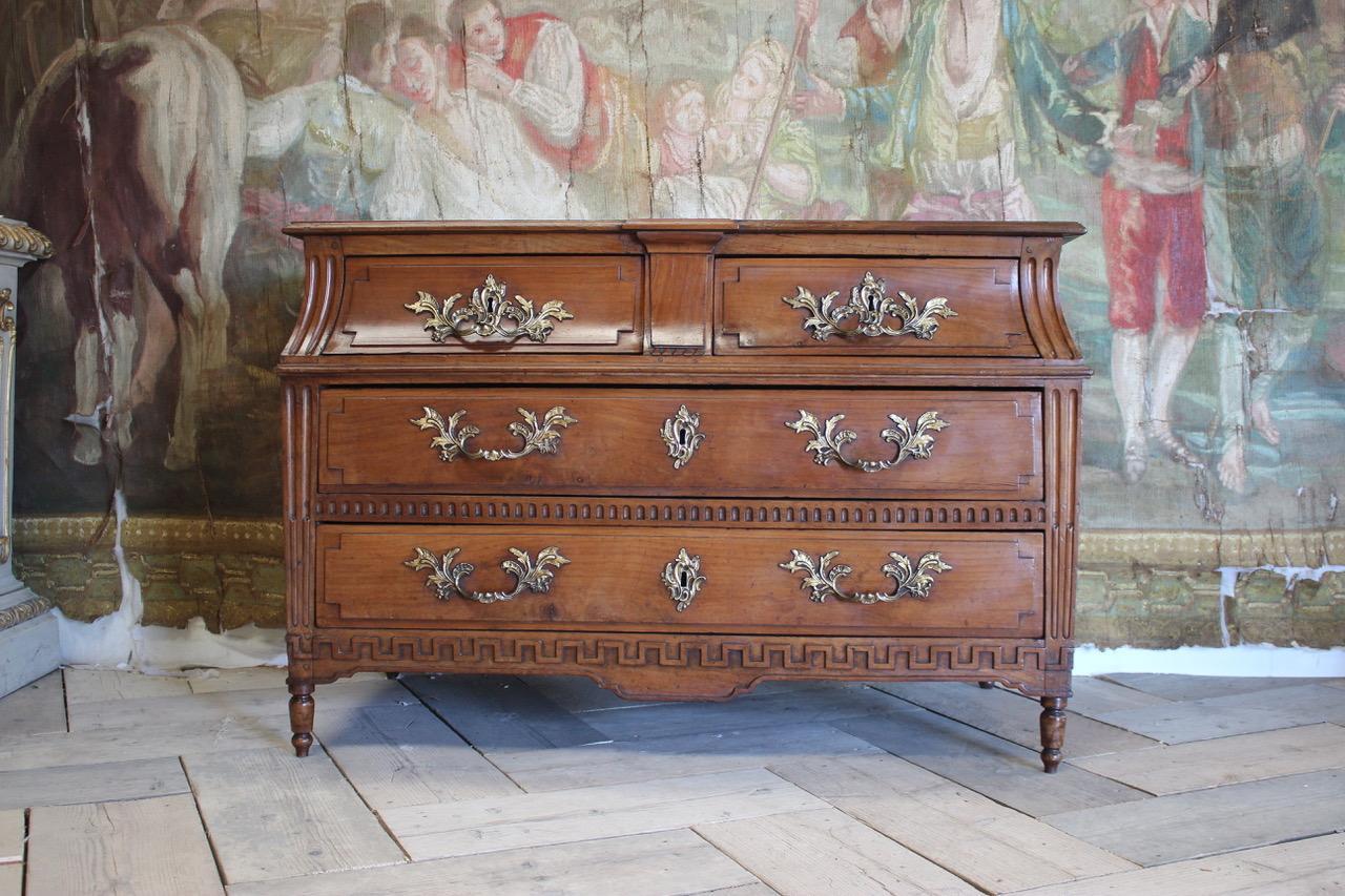 A very smart 18th century French sarcophagus shaped, cherry wood commode with gilt bronze handles and Greek key carving of elegant proportions and with a lovely color, that will make a statement in most settings.