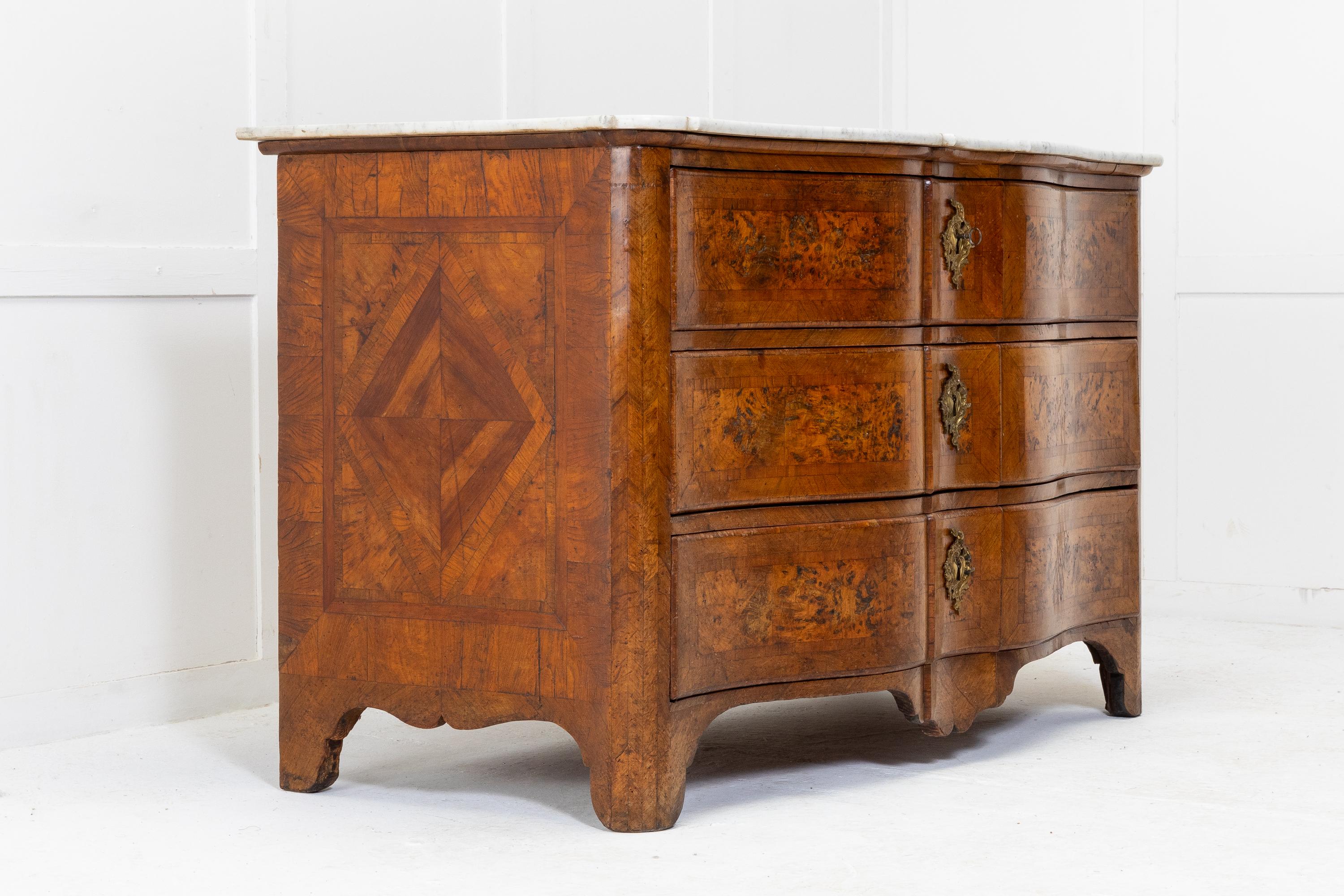 An excellent example of a maple and walnut, 18th Century serpentine fronted commode with a later marble top. Having three long drawers with burr maple panels and walnut crossbanding and central escutcheons. The sides are quarter veneered and