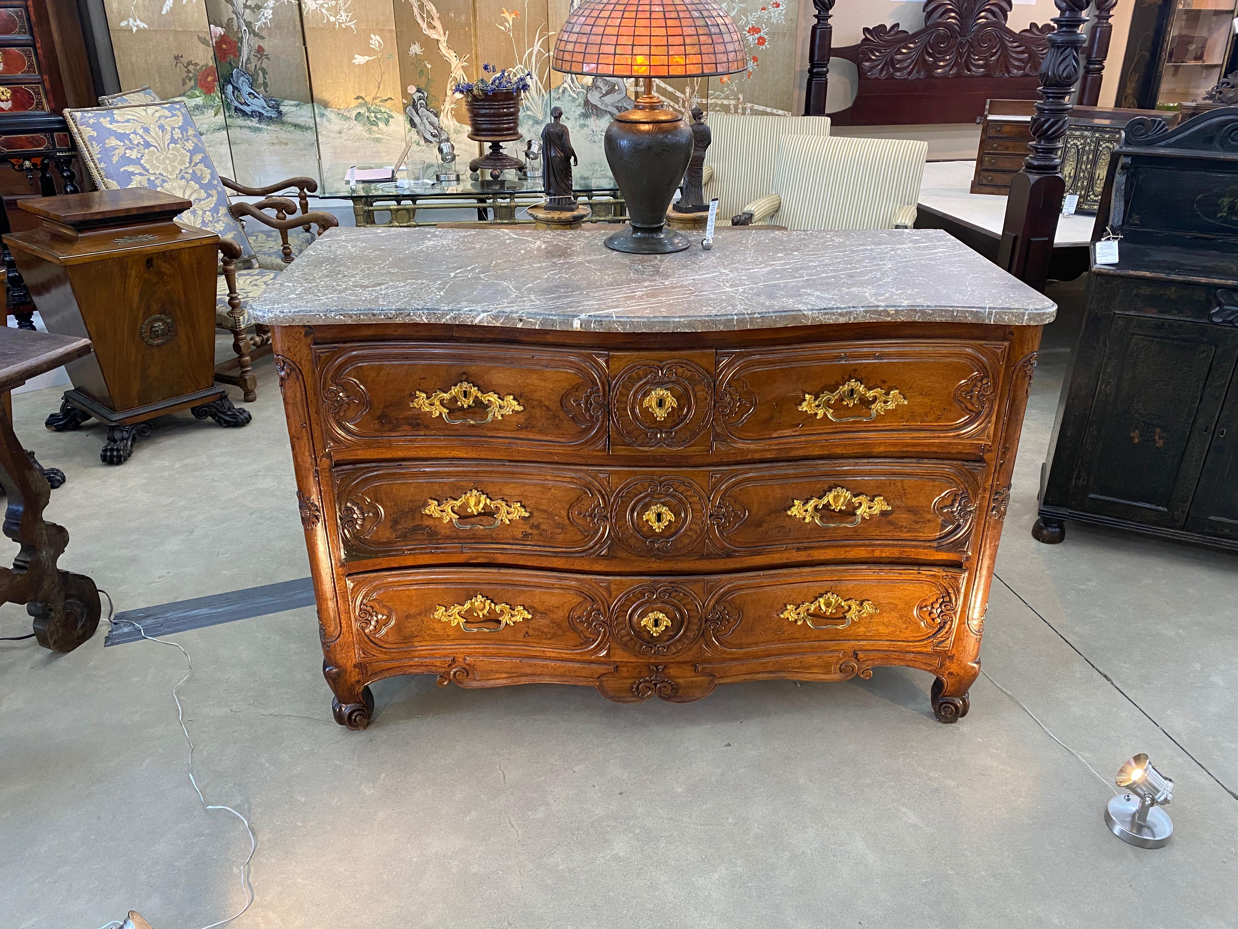 18th century French serpentine marble top walnut commode with sunflowers carved on the front corner stiles. Three drawers over two. The top row of three drawers are carved and shaped as one drawer to match the lower two drawers, see photos. Marble