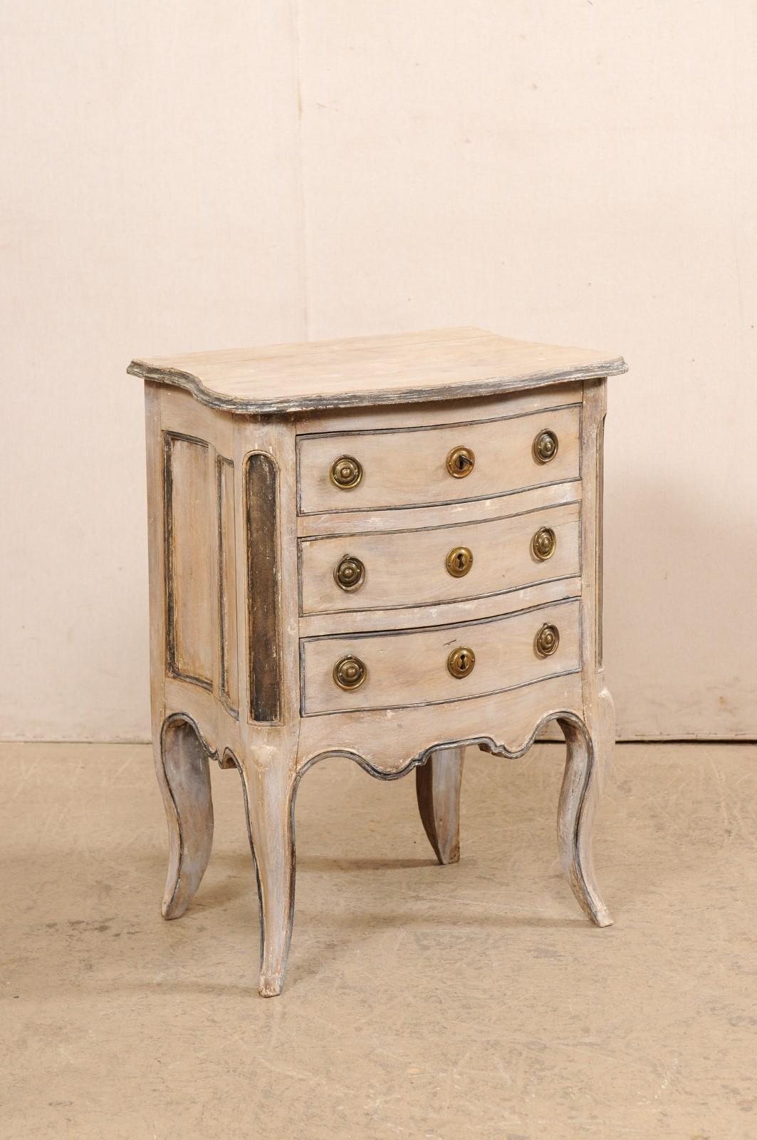 A French small-sized serpentine chest from the 18th century. This antique commode from France features a serpentine front and curvy sides, three dove-tailed drawers housed between round front side posts adorn with elongated recessed panels, and a