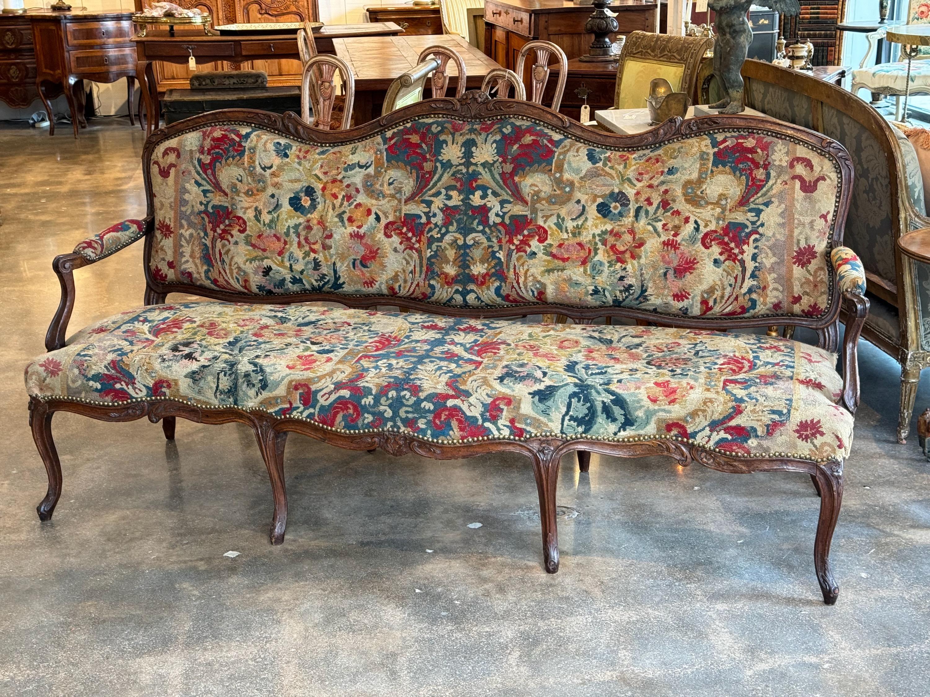 This is a beautiful French settee covered in needle point. It has graceful lines. Perfect hall bench.