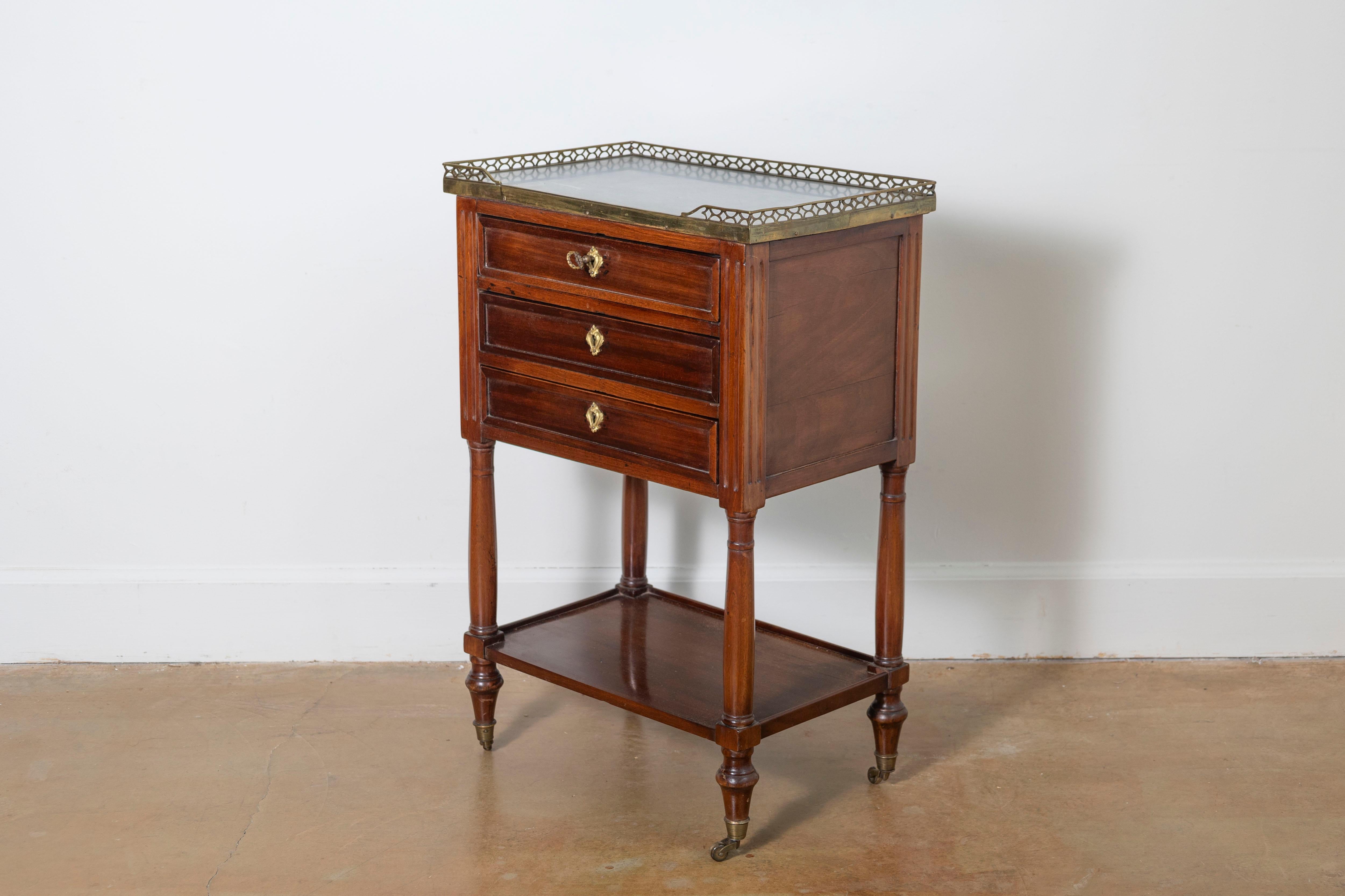 Cette exquise table d'appoint en noyer de style Louis XVI du XVIIIe siècle reflète l'élégance intemporelle et le savoir-faire artisanal du design français. Fabriqué en acajou riche, il comporte trois tiroirs à fonctionnement souple avec d'élégantes