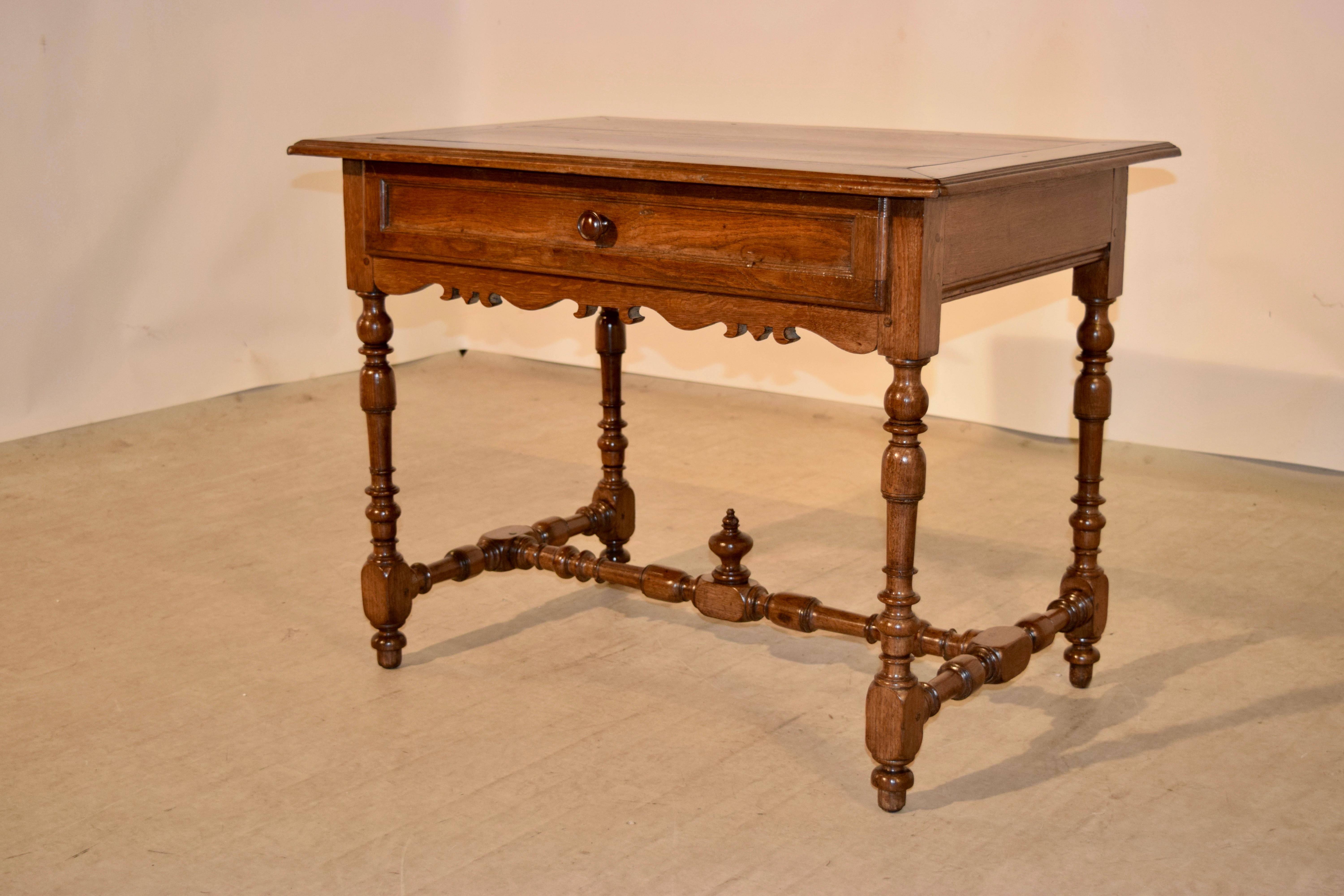 18th Century side table from France with a nicely banded top, following down to a simple apron with a single drawer, which has a paneled drawer front and a hand scalloped apron below. The legs are wonderfully hand-turned and joined by matching