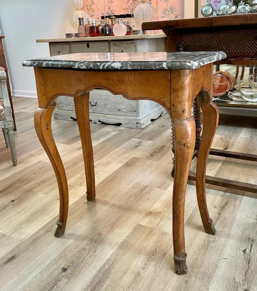 Fine table d'appoint française du 18ème siècle, Louis XV,  avec un plateau en marbre, une jupe figurée et des pieds courbés reposant sur des sabots stylisés.  28,5