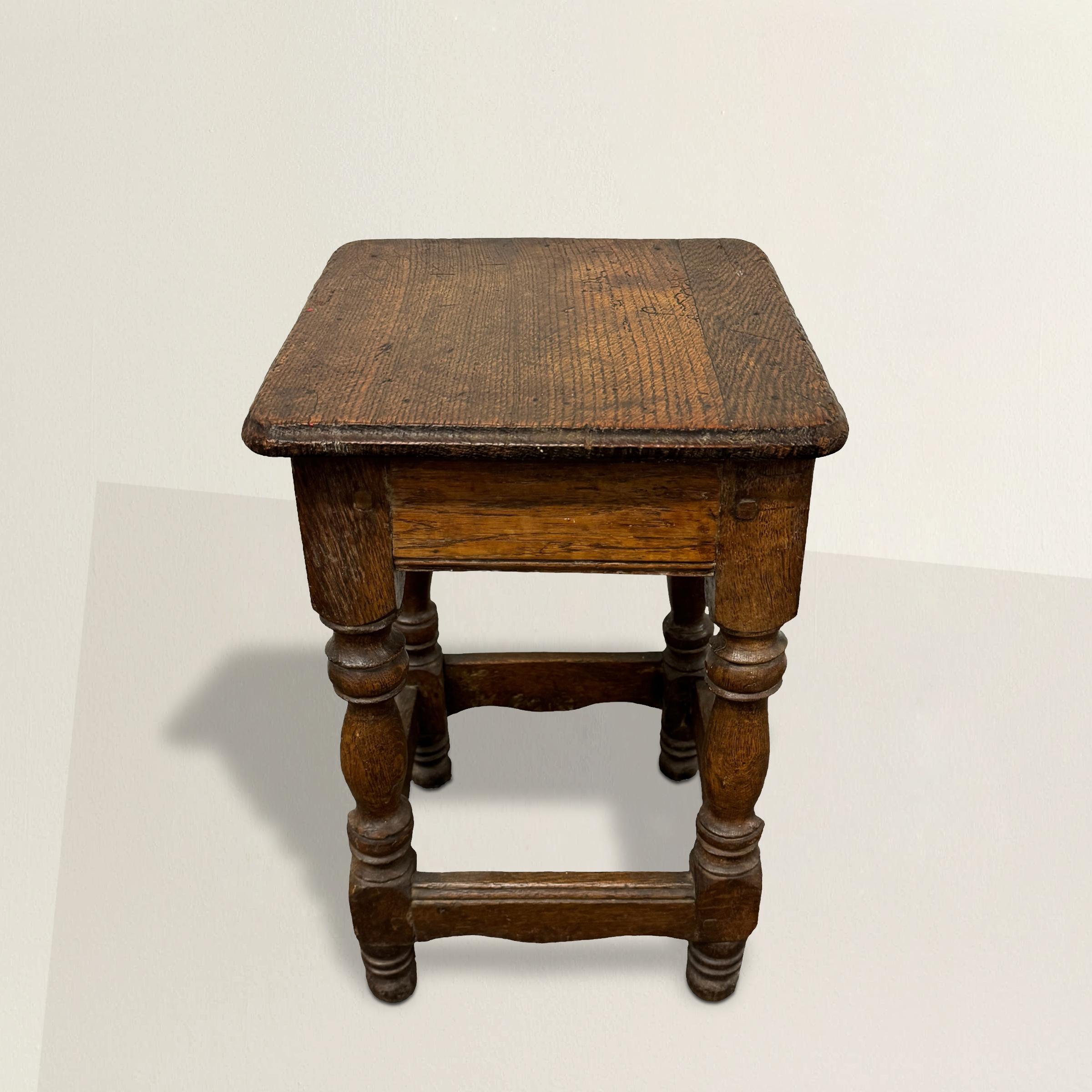 Ce tabouret en chêne tourné français du XVIIIe siècle est un magnifique exemple d'élégance intemporelle et d'artisanat exquis. Avec ses pieds joliment tournés, son tablier délicatement enroulé et son repose-pieds, ce tabouret respire le charme et la