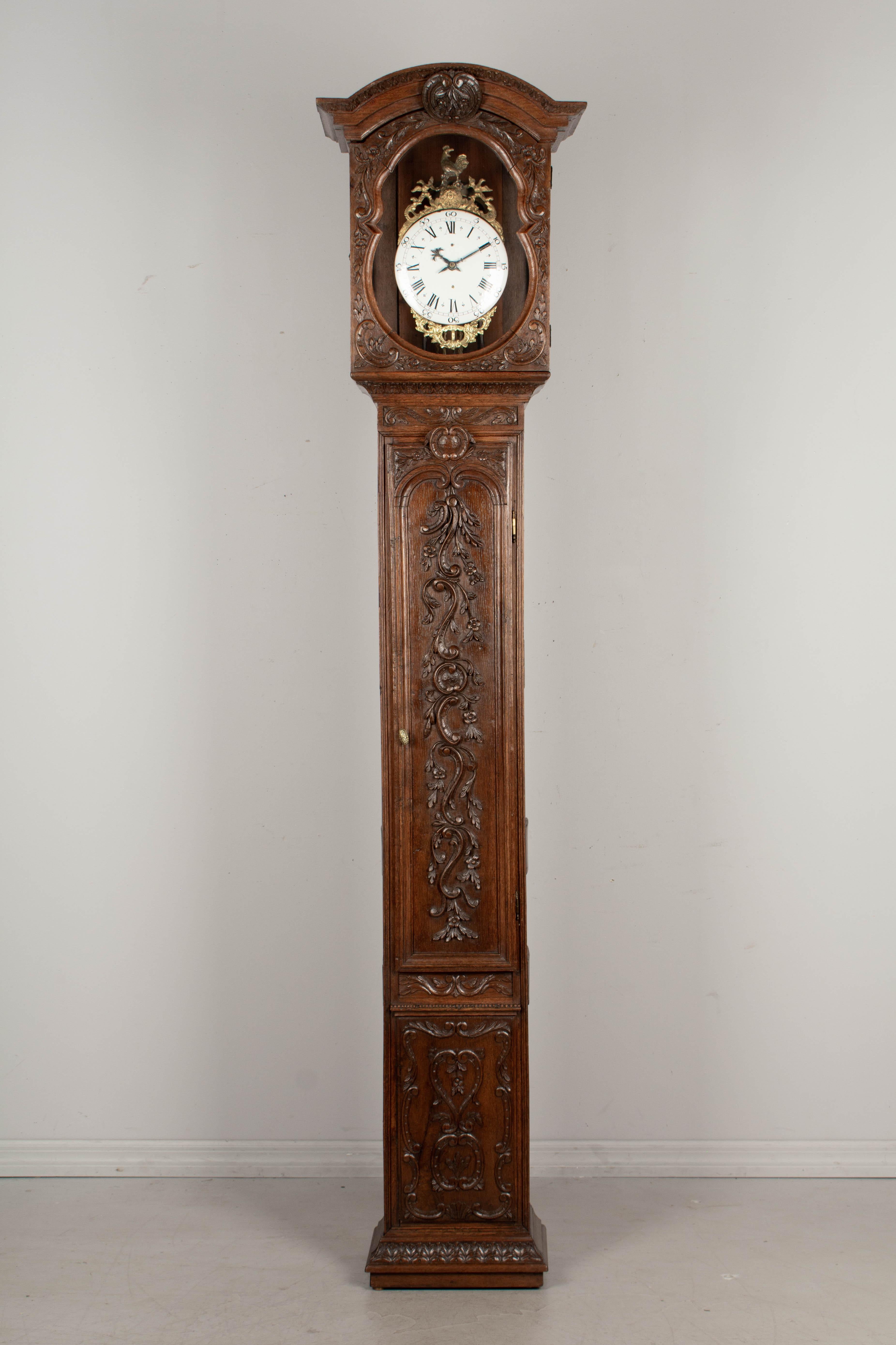 An 18th century tall case clock from Normandy. The case is made of oak with beautiful floral carved relief and waxed patina. Cast brass clock surround with rooster. The 18th century one day movement has been professionally cleaned and is in working