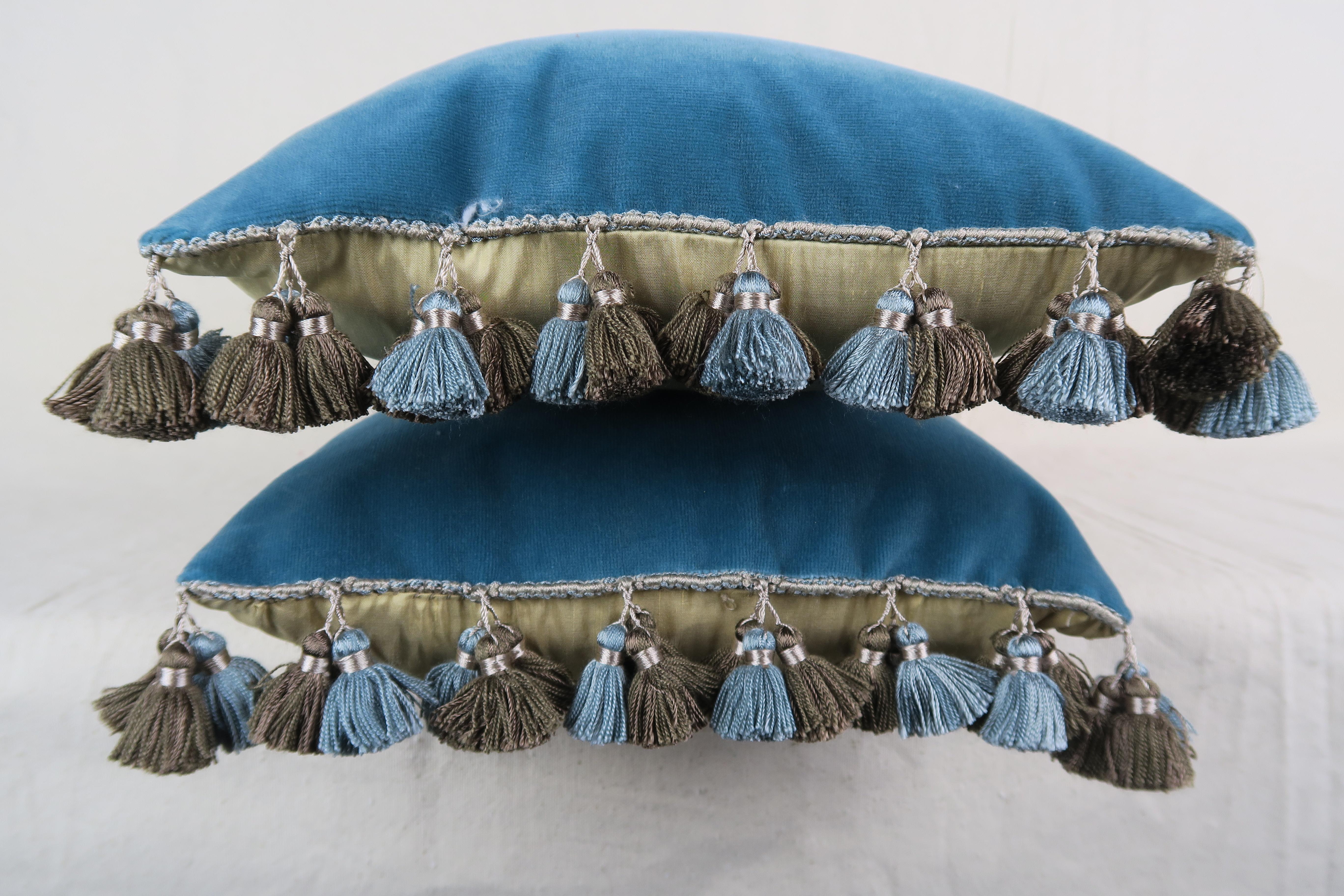 Pair of custom pillows made with 18th century handmade tapestry pieces combined with contemporary blue velvet fronts and silk backs. multicolored tassel fringe at sides of pillows. Down and feather inserts, sewn closed.