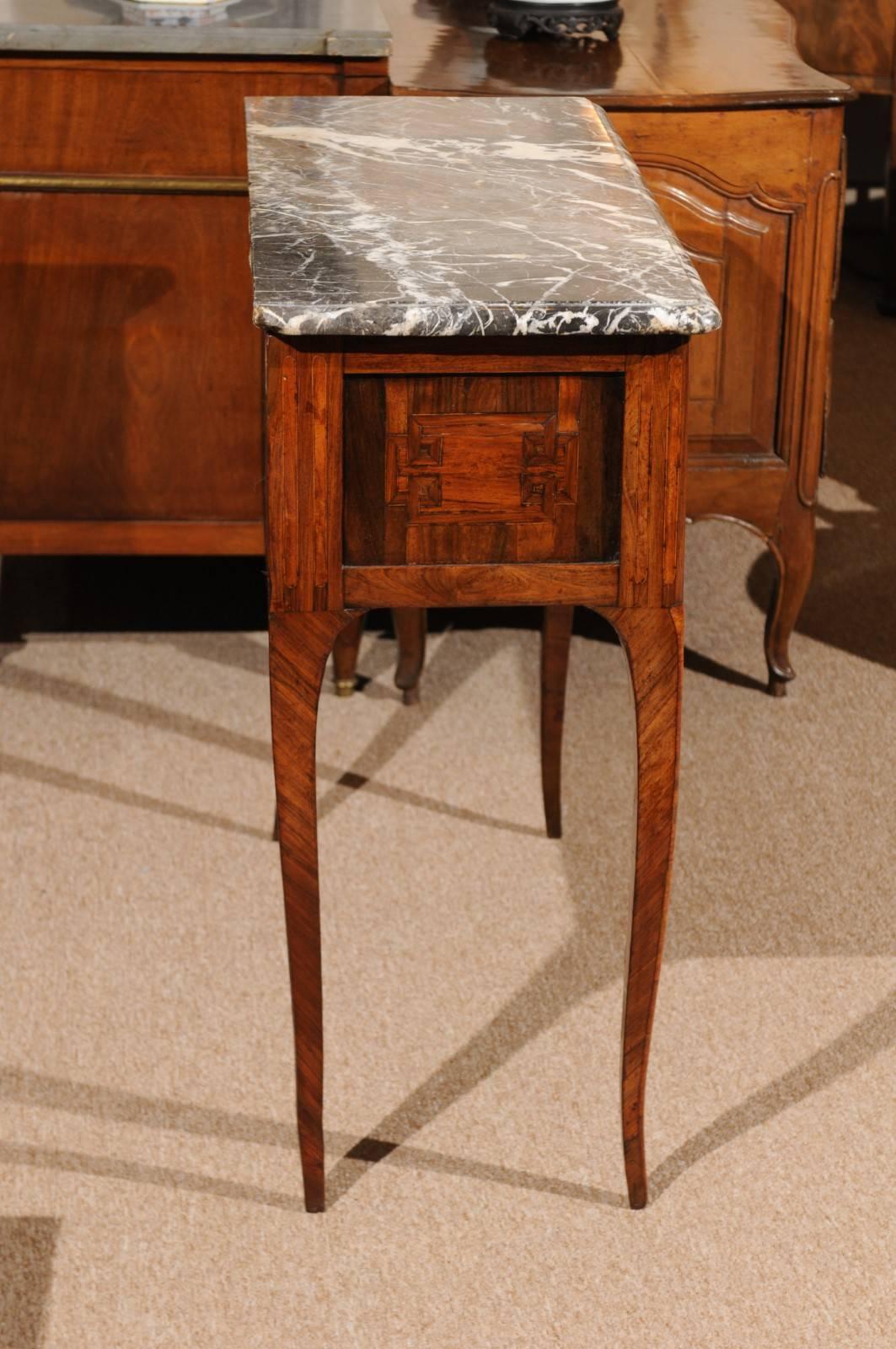 The commode en console with grey marble top resting on rectangular base in walnut and tulipwood with cross-banding and inlay to drawer and brass ring pulls. All resting on cabriole legs.



    