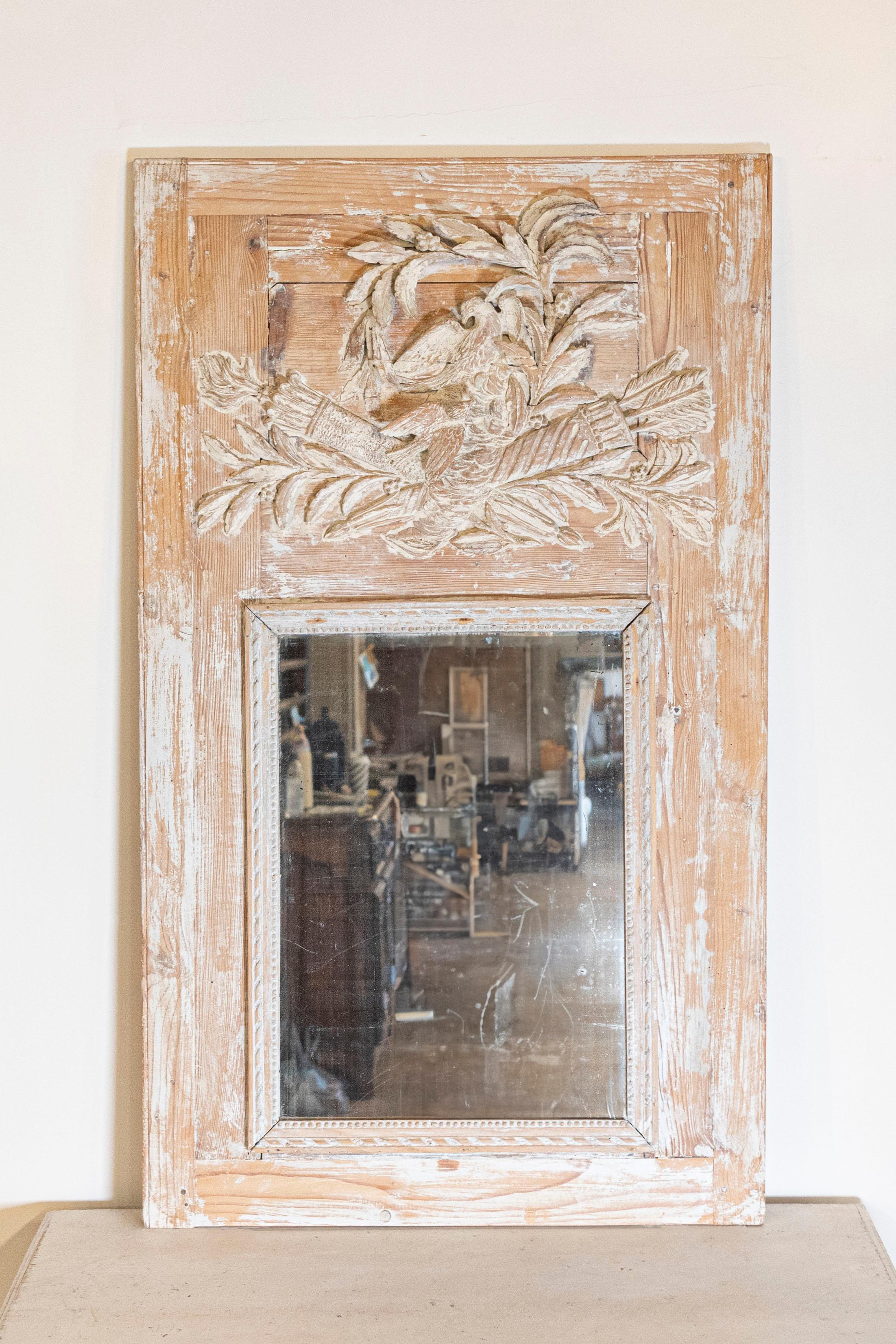 Cet exquis miroir Trumeau français du XVIIIe siècle, vers 1790, est un exemple étonnant d'artisanat néoclassique et d'élégance intemporelle. Sculpté dans du pin, un bois traditionnellement utilisé dans les arts décoratifs français pour sa