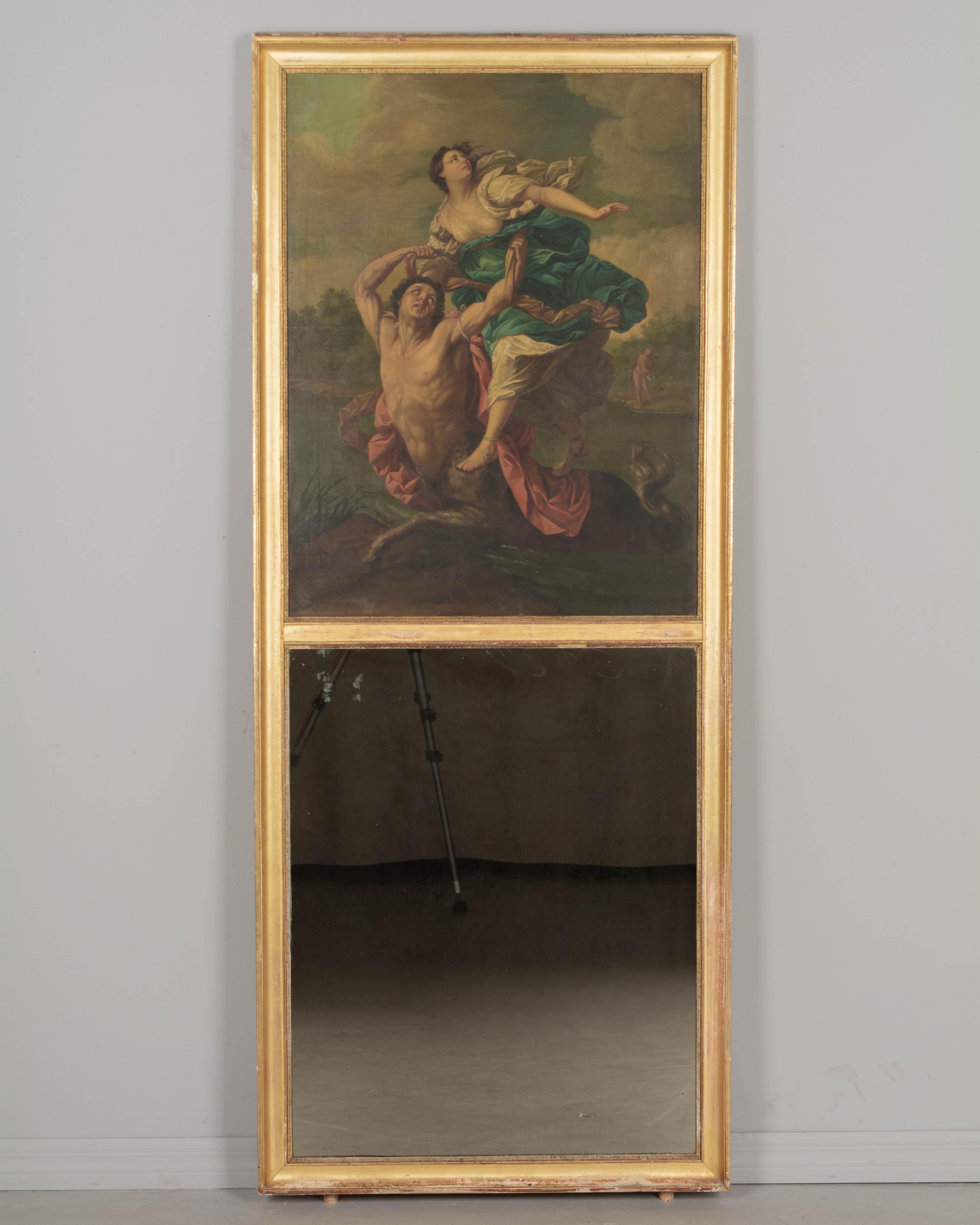 An 18th century French Louis XVI style trumeau mirror with a large oil painting depicting The Abduction of Deianira after Guido Reni. Gilded wood frame with bright gilt finish is in good condition with small losses along bottom edge and minor