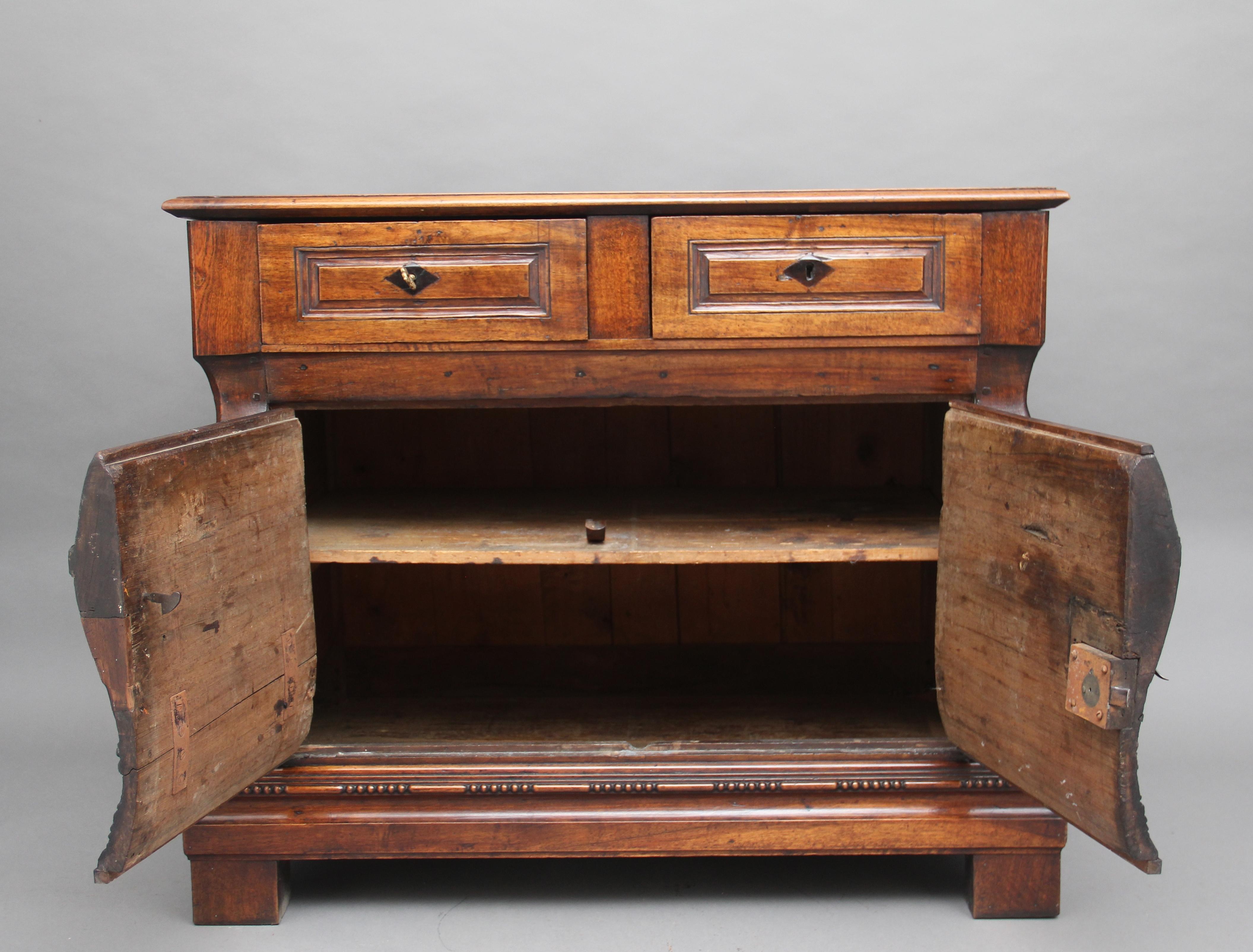 An unusual and rare 18th century French walnut Bombay commode, the thumb moulded edge above two large drawers with original locks, and moulded drawer fronts, two shaped cupboard doors below opening to reveal a fixed single shelf inside, the door