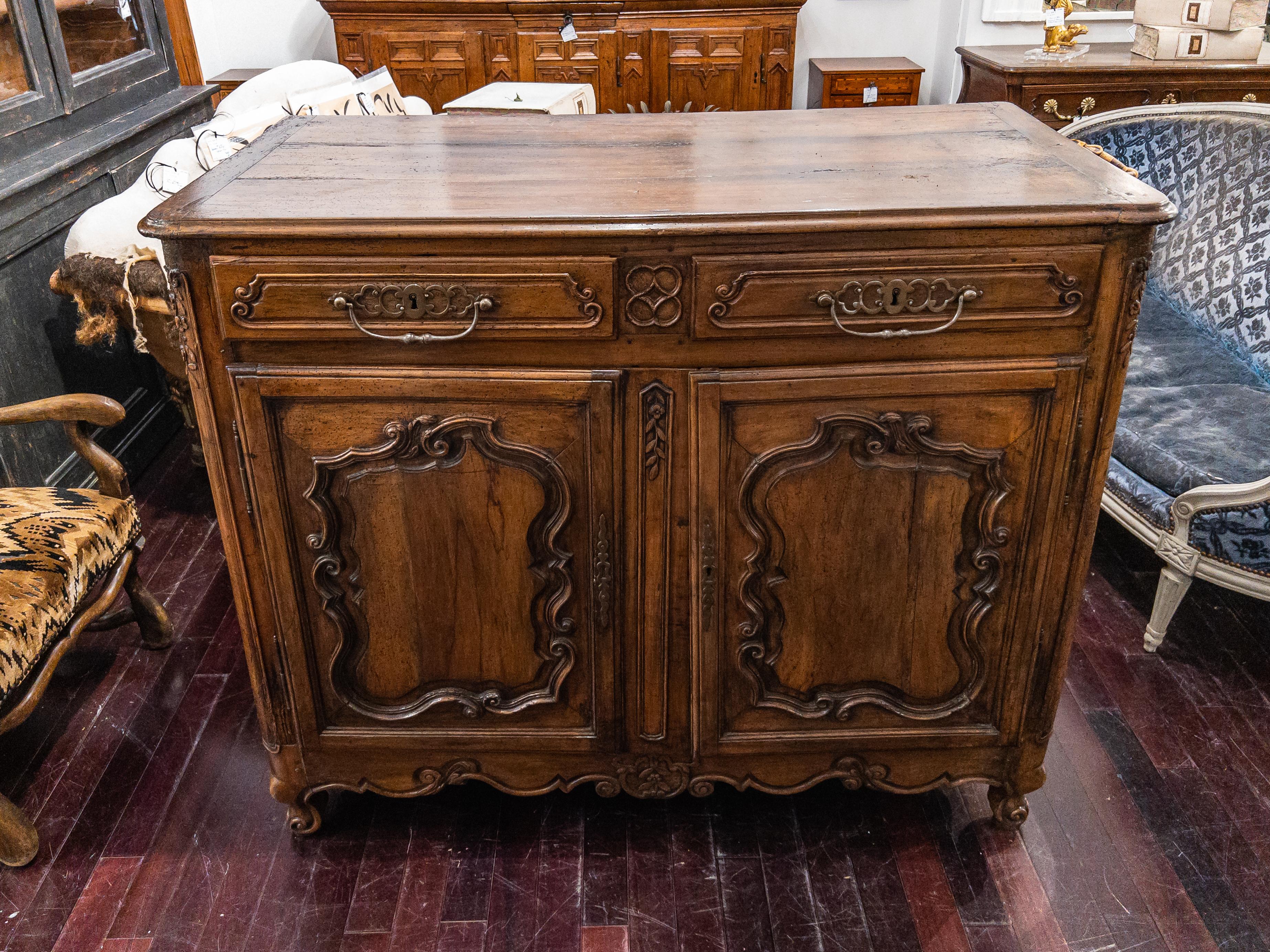 18th Century Walnut French Buffet. This lovely cabinet is a genuine antique and dates to the 18th century. It features two hand carved drawers over two paneled cupboard doors, a scalloped apron on cabriole feet and a beautiful patina.

Please